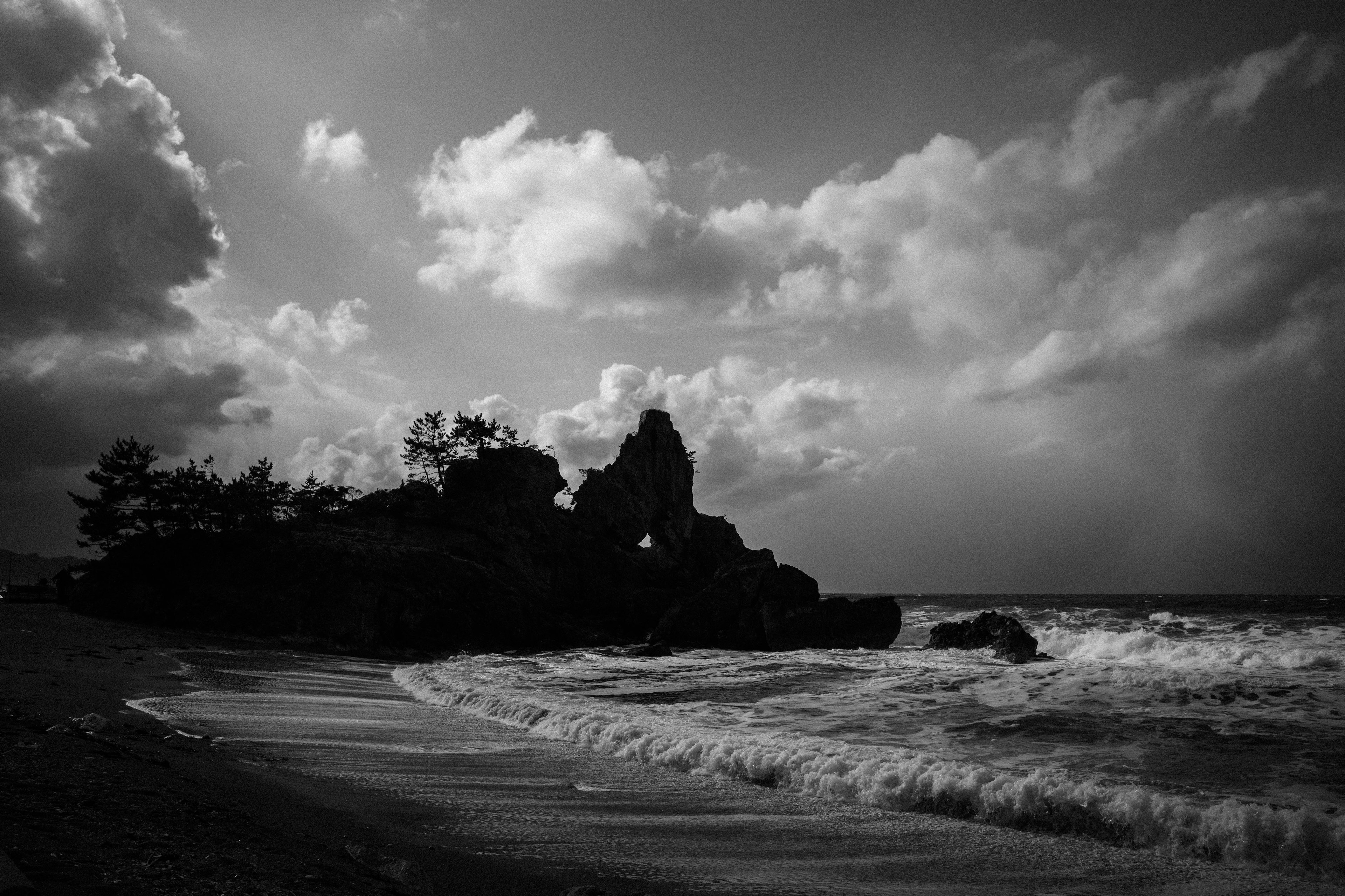 Imagen en blanco y negro de un paisaje costero con rocas y olas