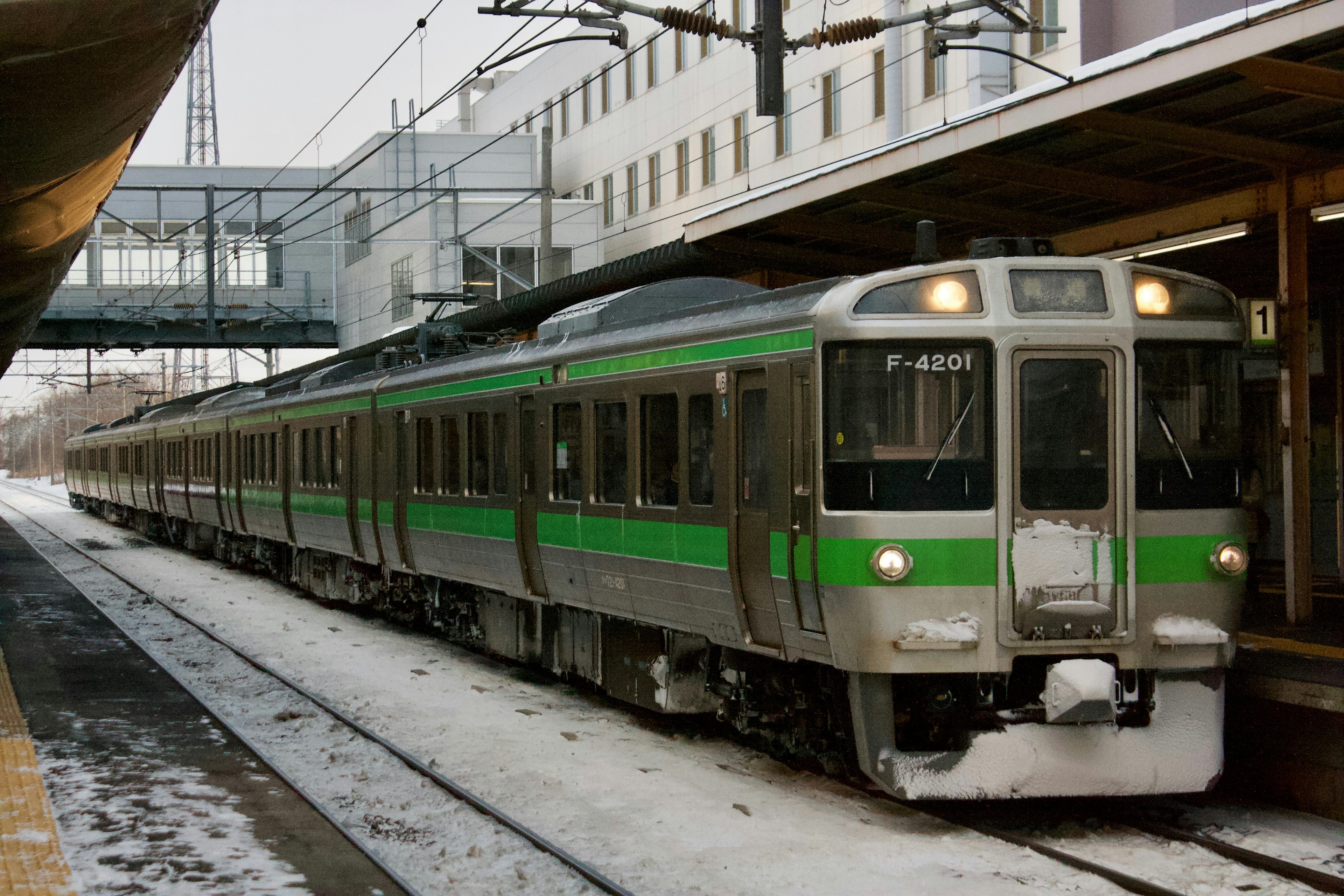 Train with green accents parked at a snowy station