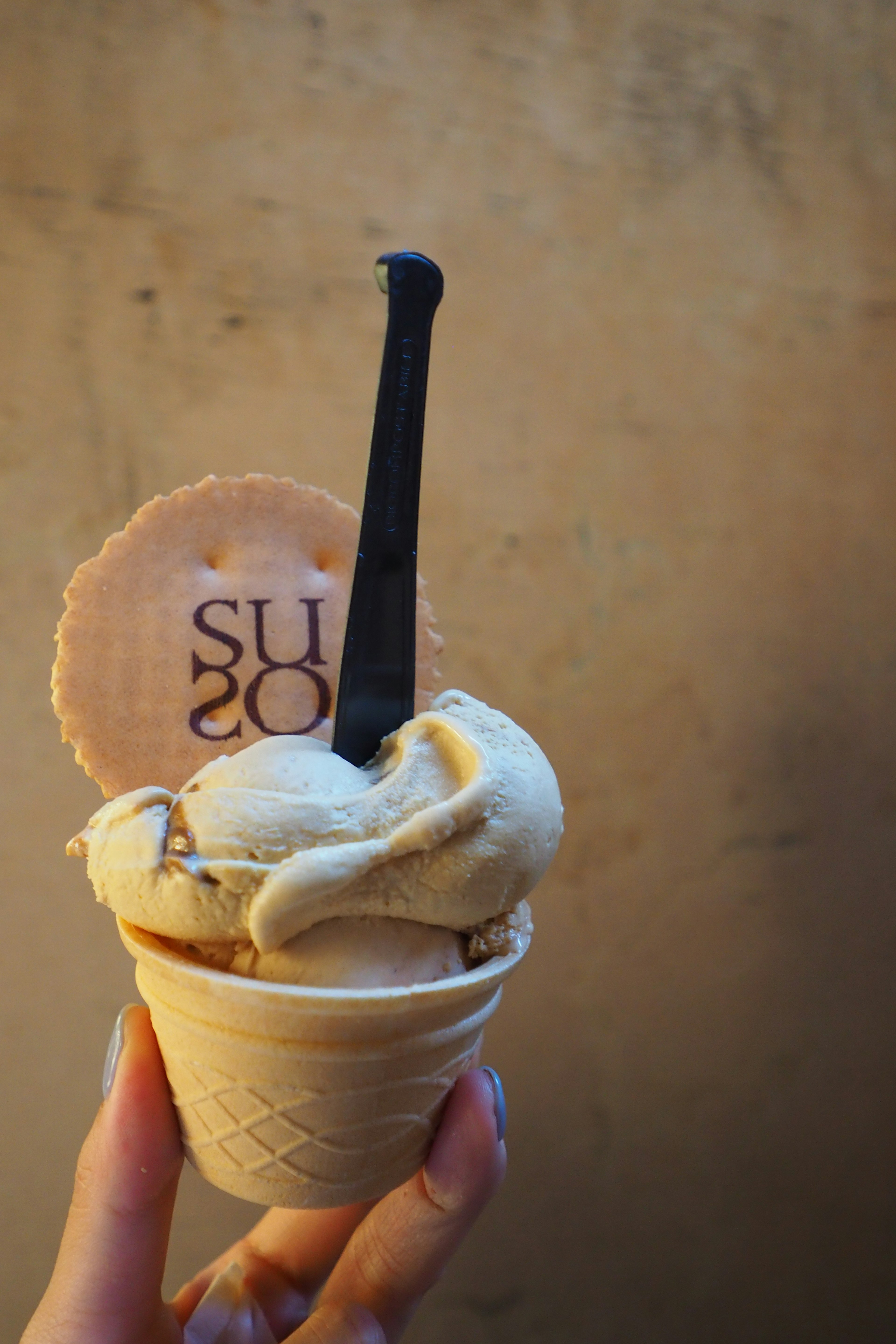 A woman holding a cone filled with cream-colored ice cream