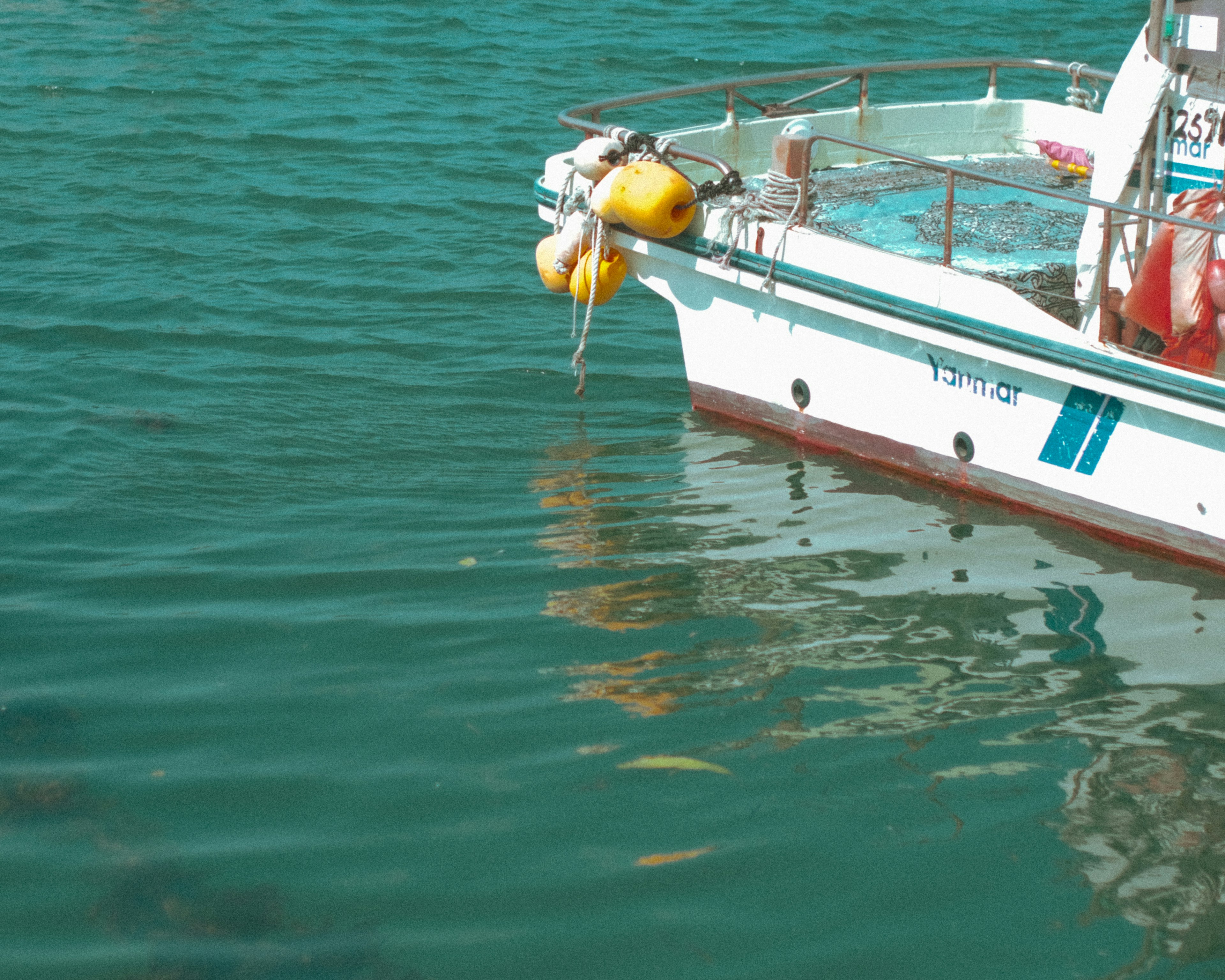 Bateau de pêche blanc flottant sur l'eau bleue avec une bouée attachée