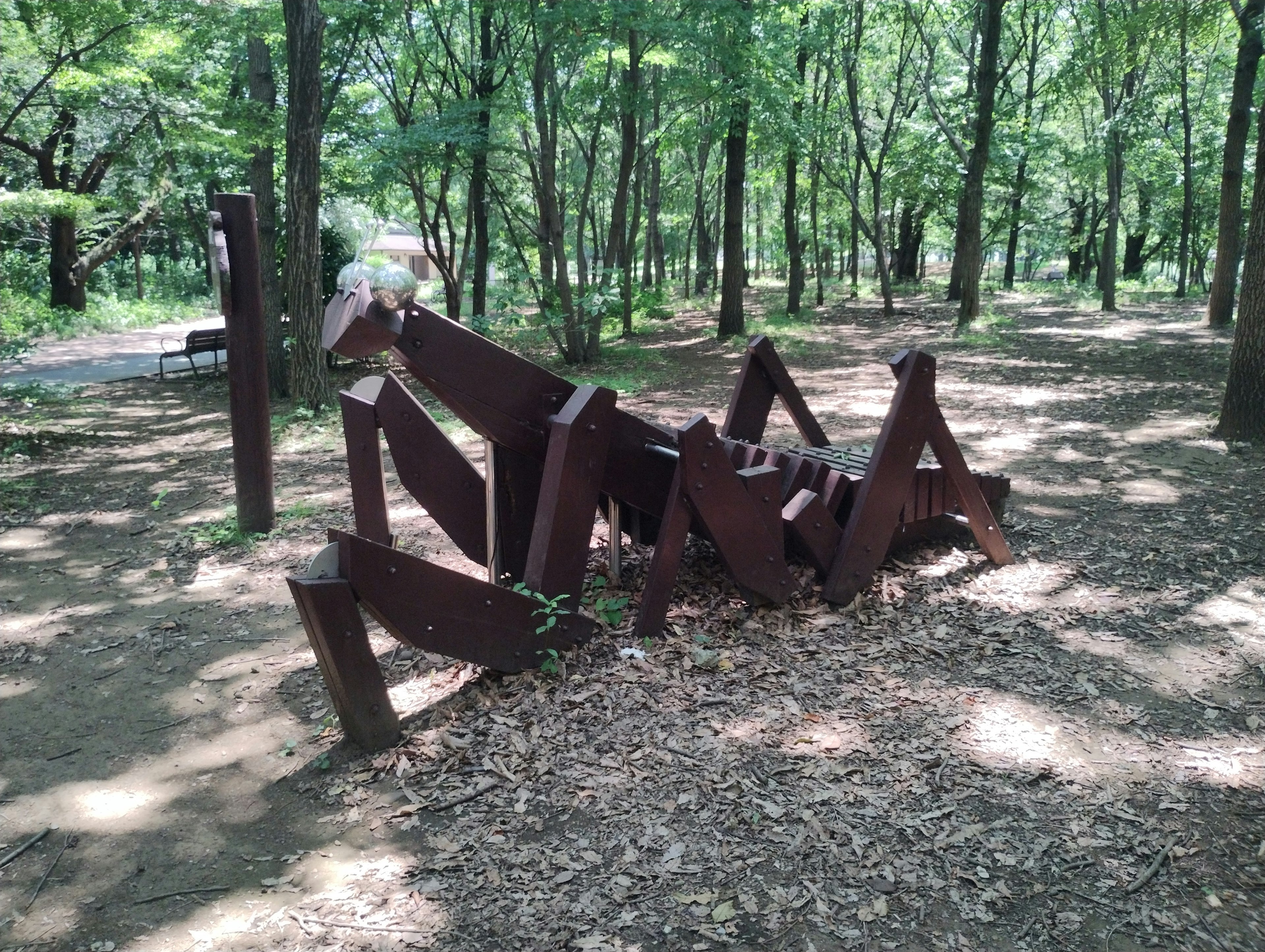 公園中的木製昆蟲雕塑，四周環繞著綠色樹木