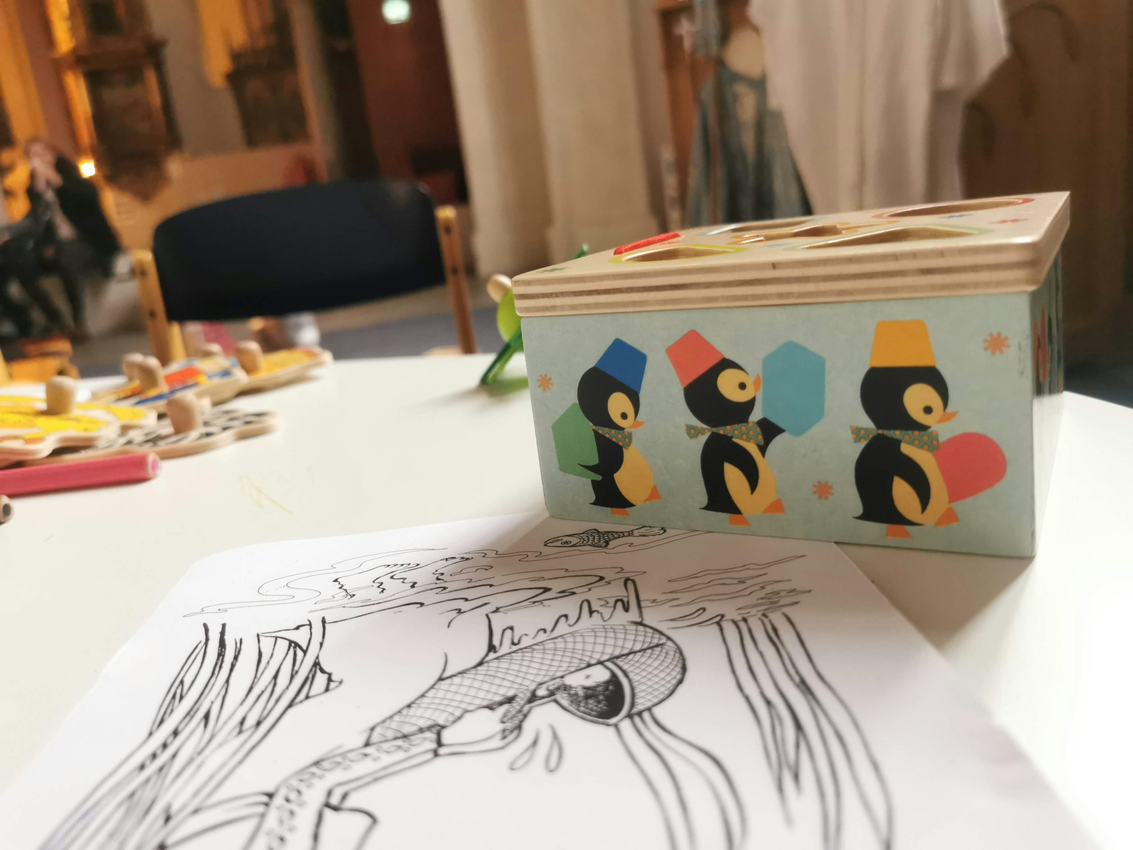 Colorful box featuring penguins on a table with a coloring page