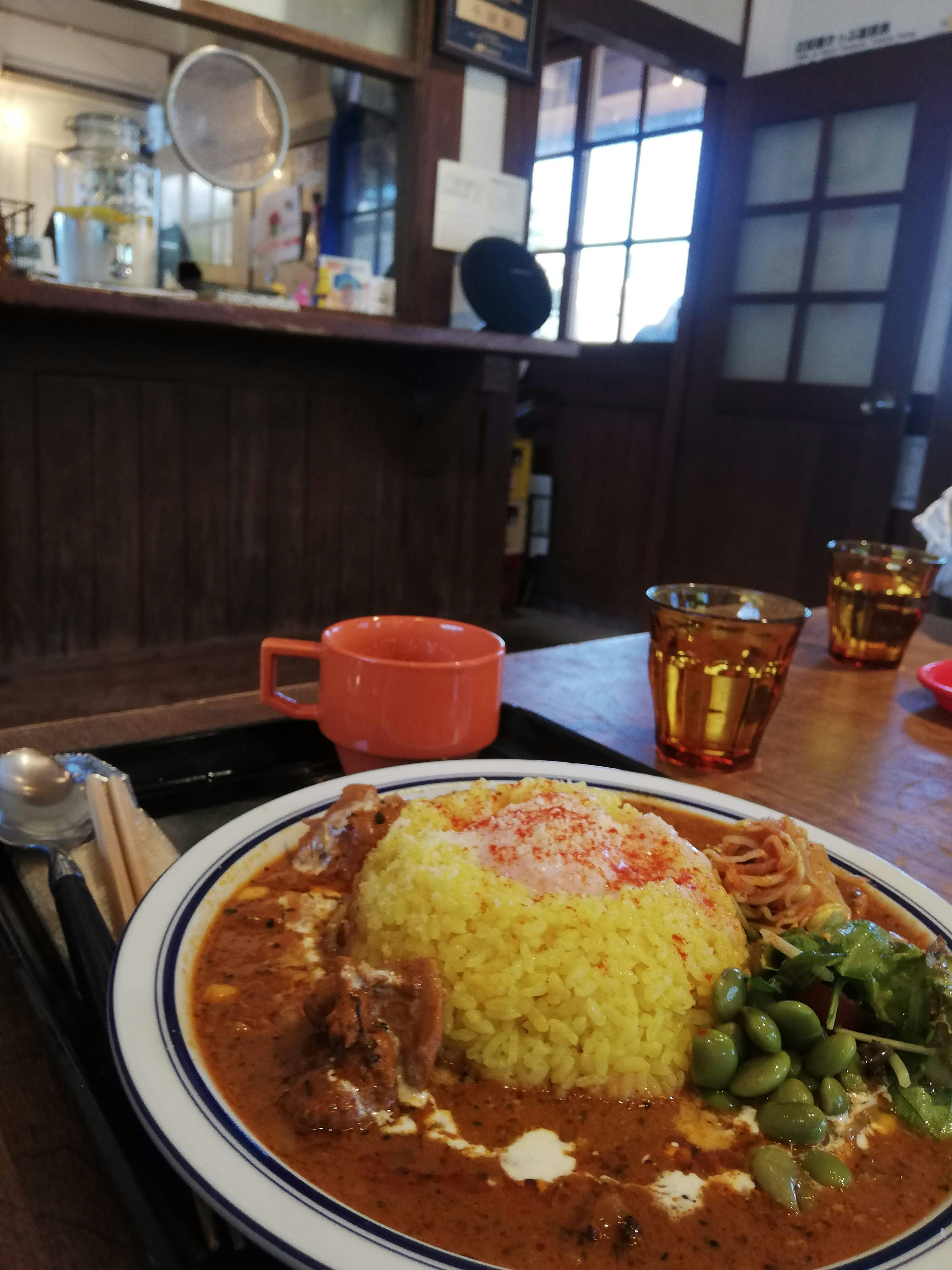 Teller mit Curry und Reis mit bunter Präsentation und Café-Hintergrund