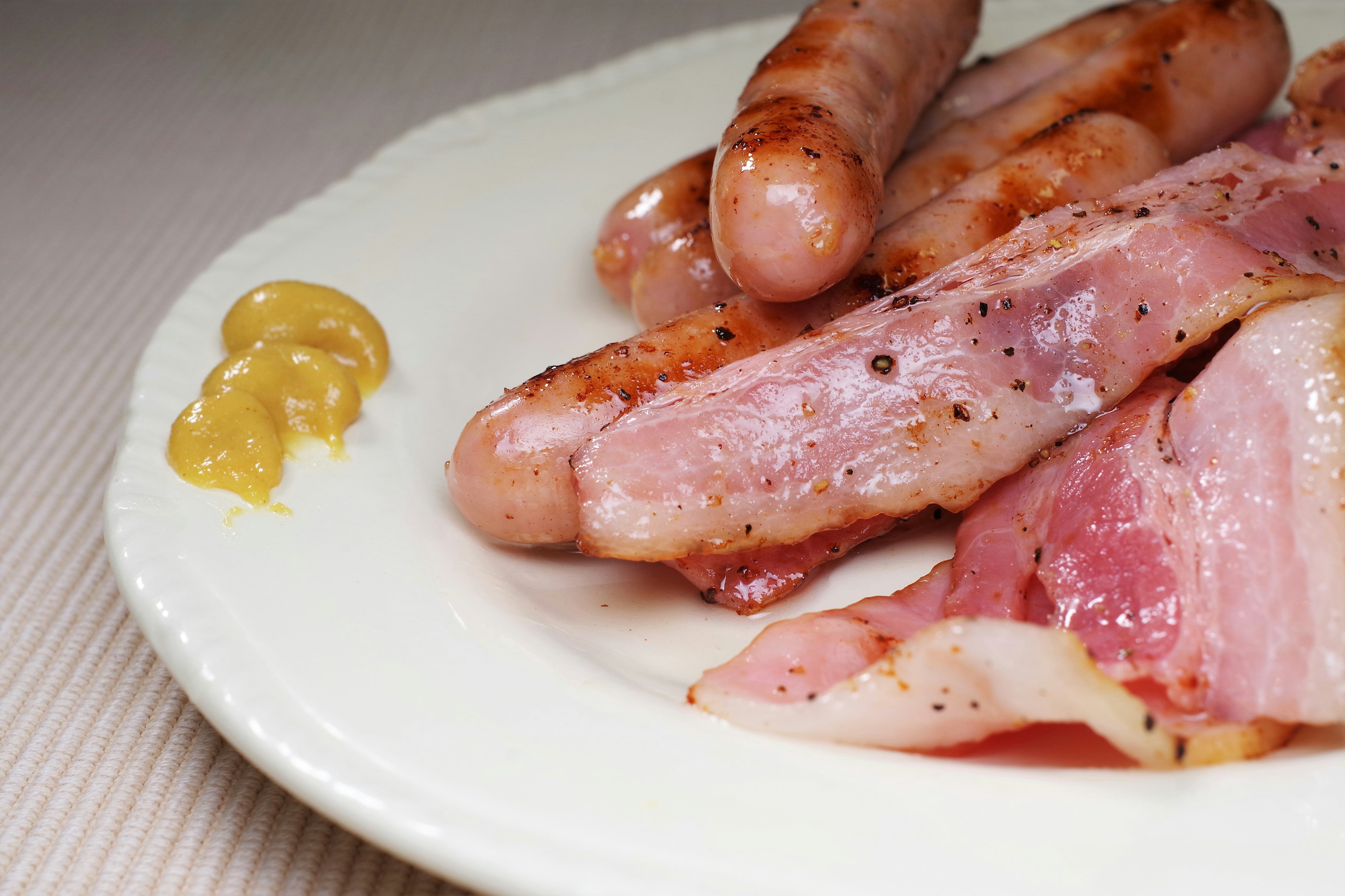 Assiette de saucisses et de bacon avec de la moutarde à côté