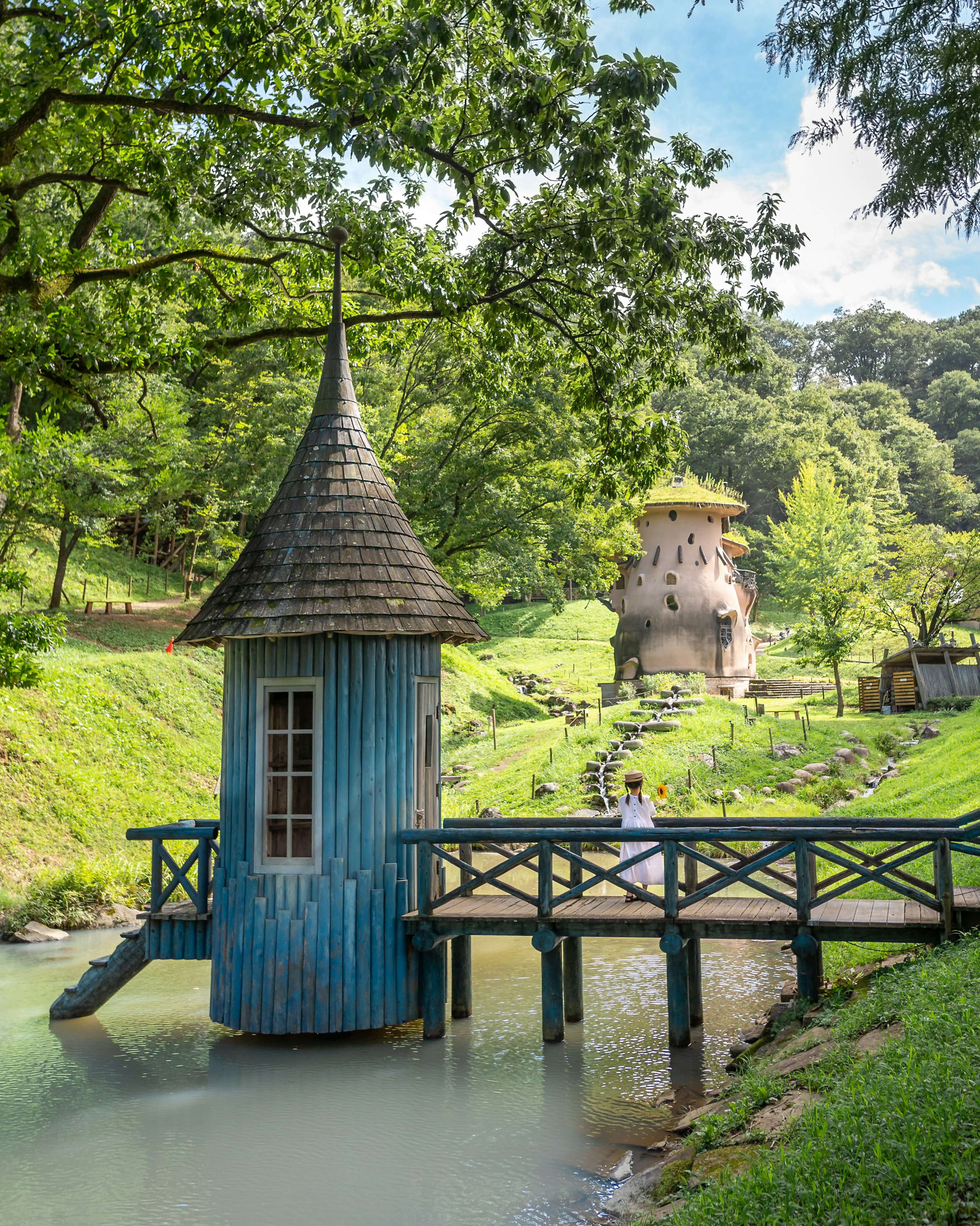 青い小屋と橋がある緑豊かな風景