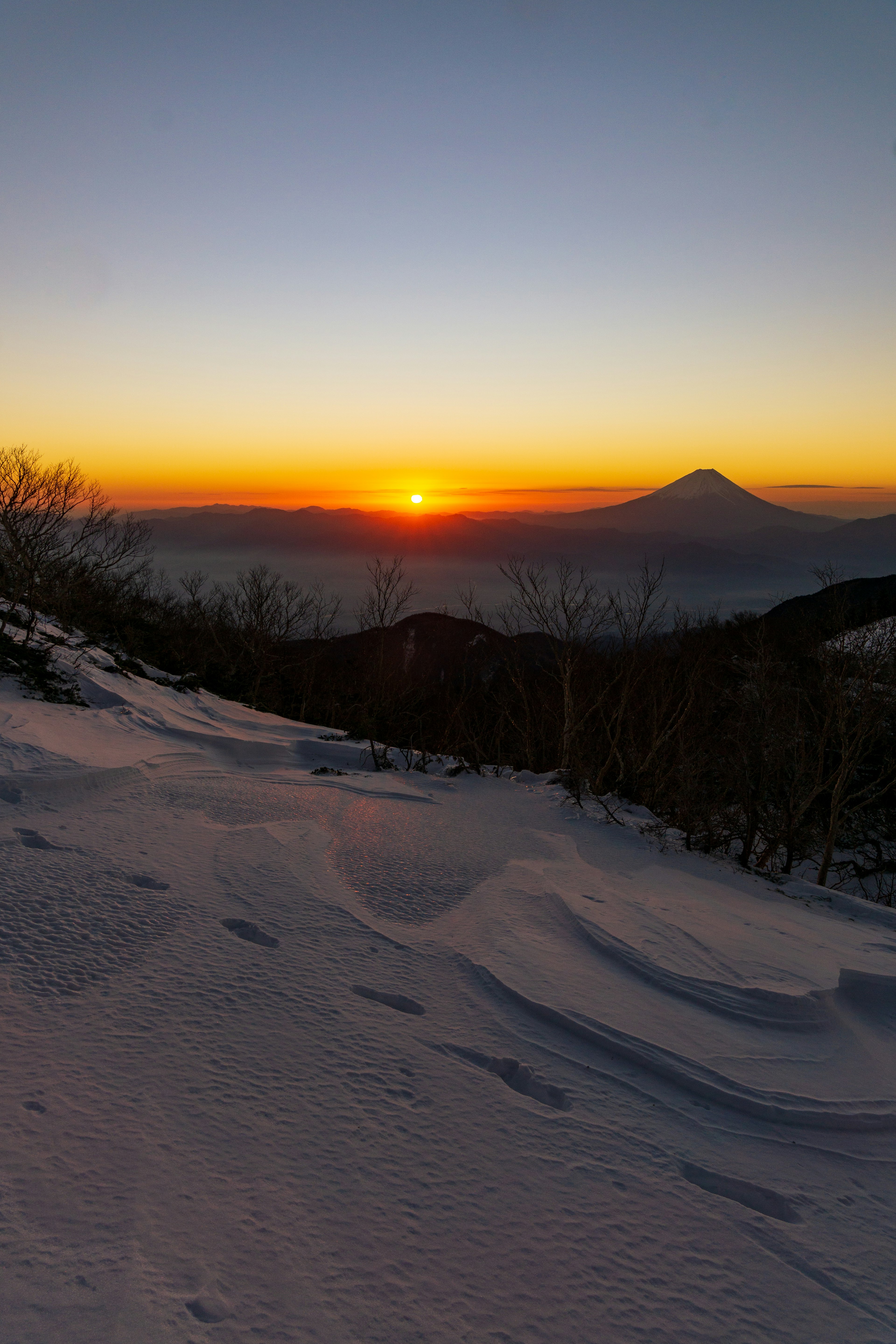 Magnifique lever de soleil sur une pente de montagne enneigée avec le mont Fuji au loin