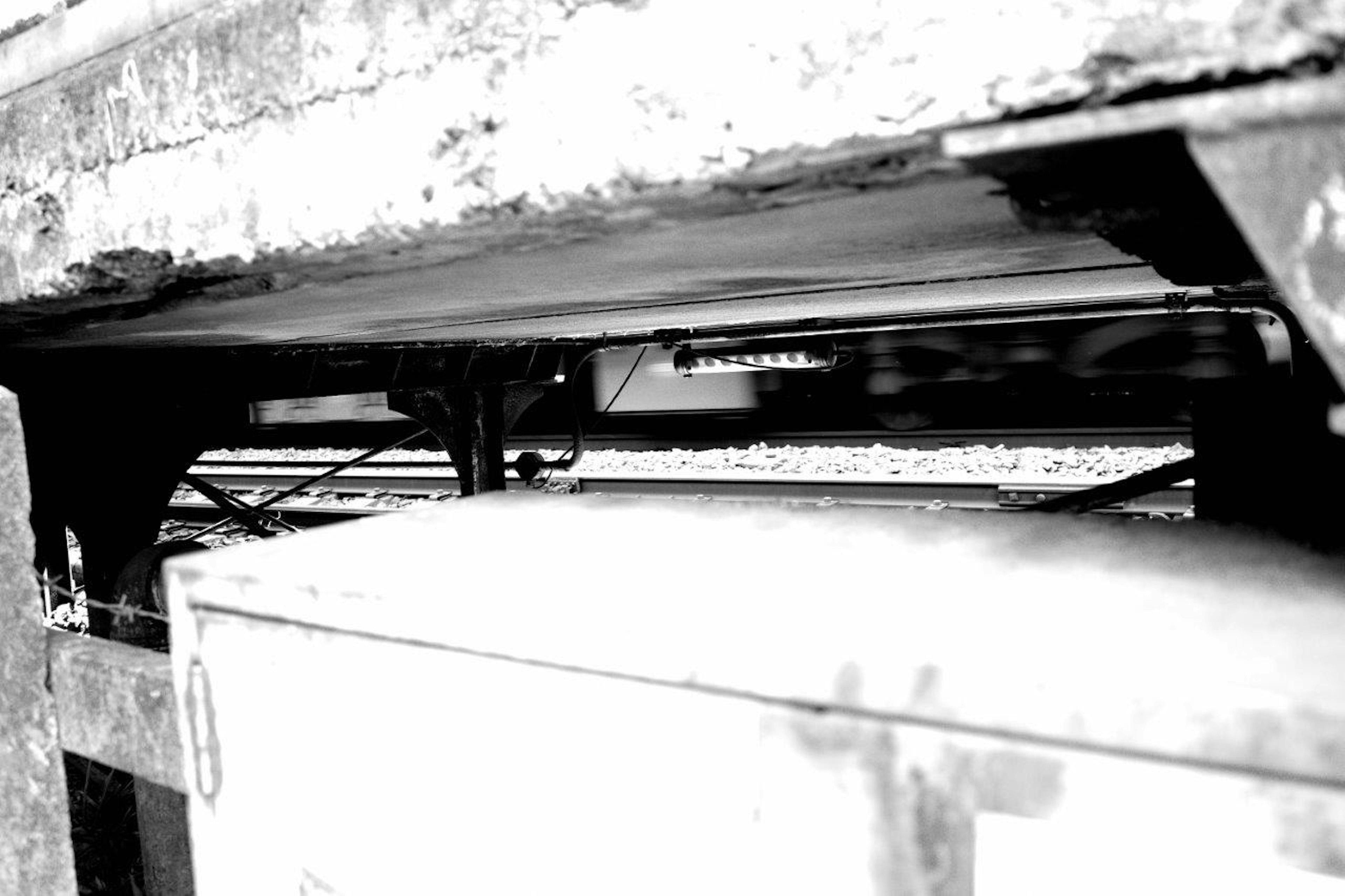 Close-up of railway undercarriage in black and white showing weathered wood and metal components