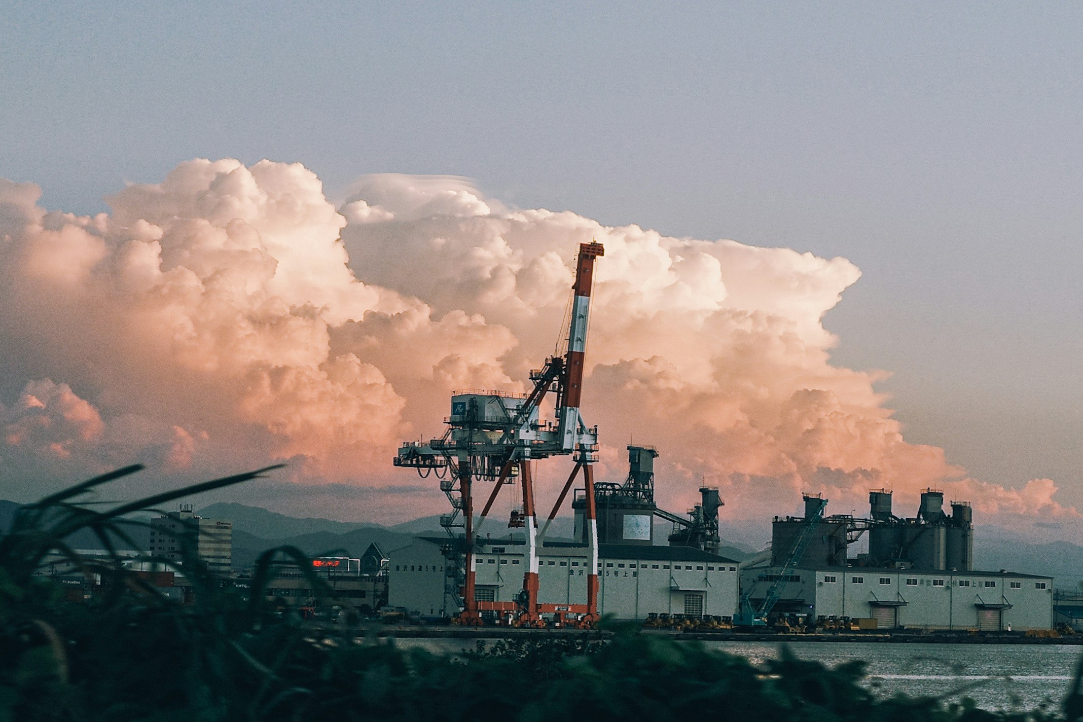 Paesaggio industriale con una gru e edifici di fabbrica sotto un cielo al tramonto colorato