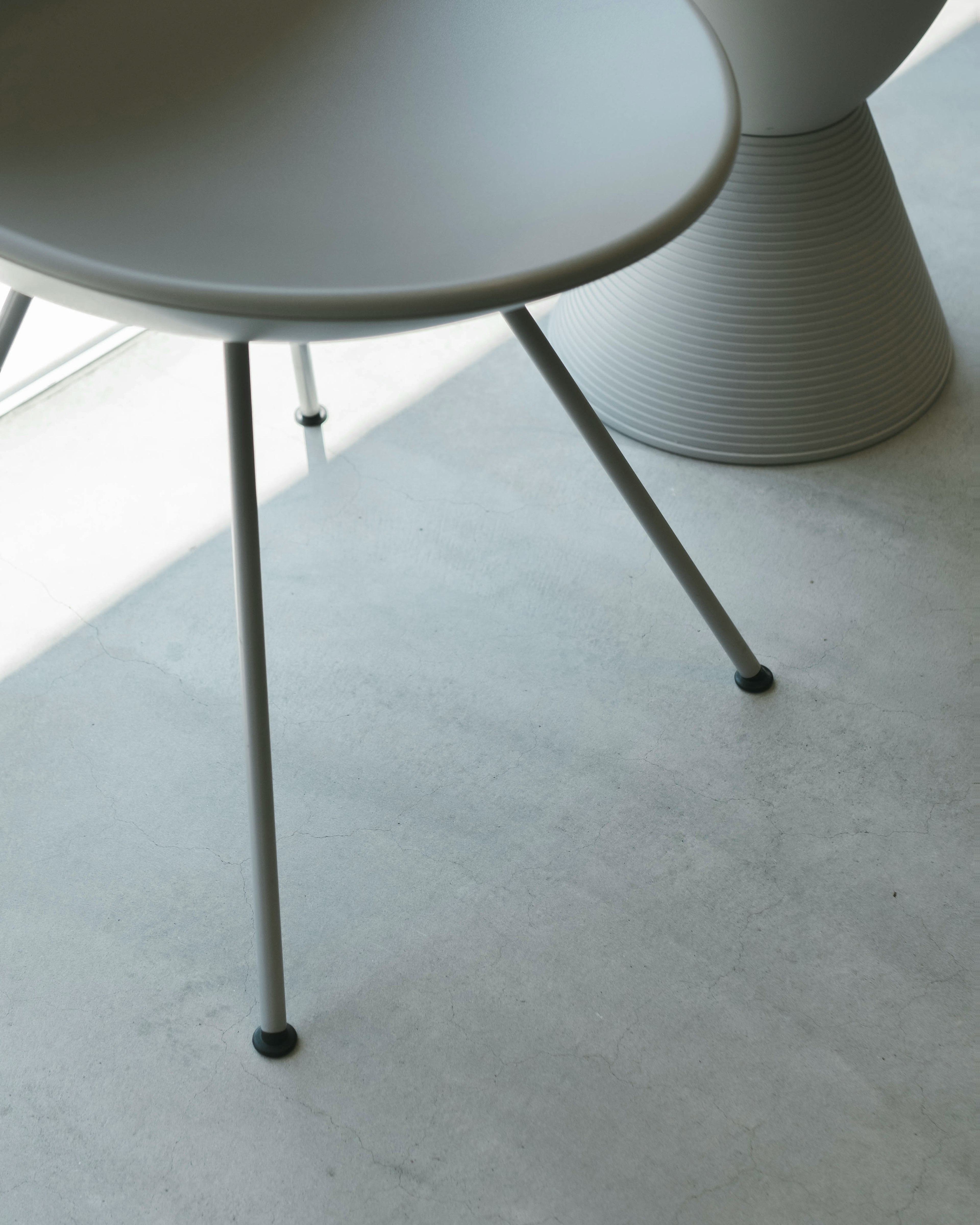 A minimalistic interior featuring a gray chair and a cone-shaped table