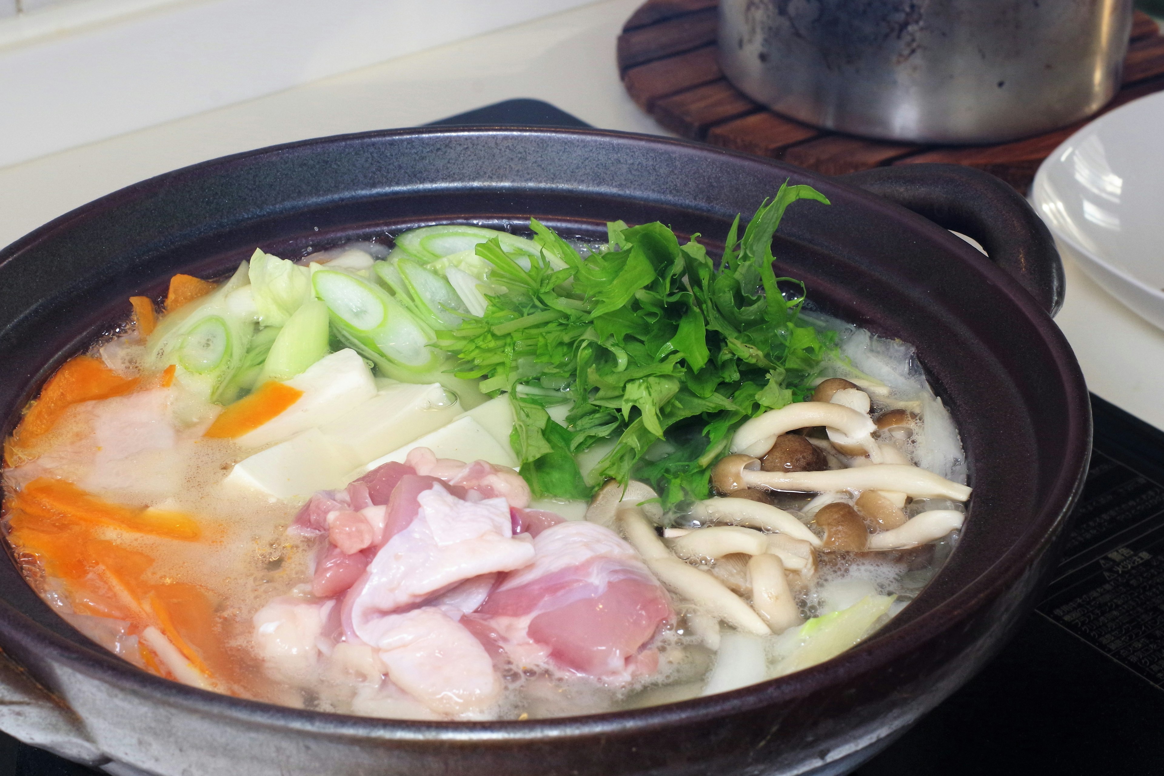 A vibrant hot pot filled with vegetables and sliced meat