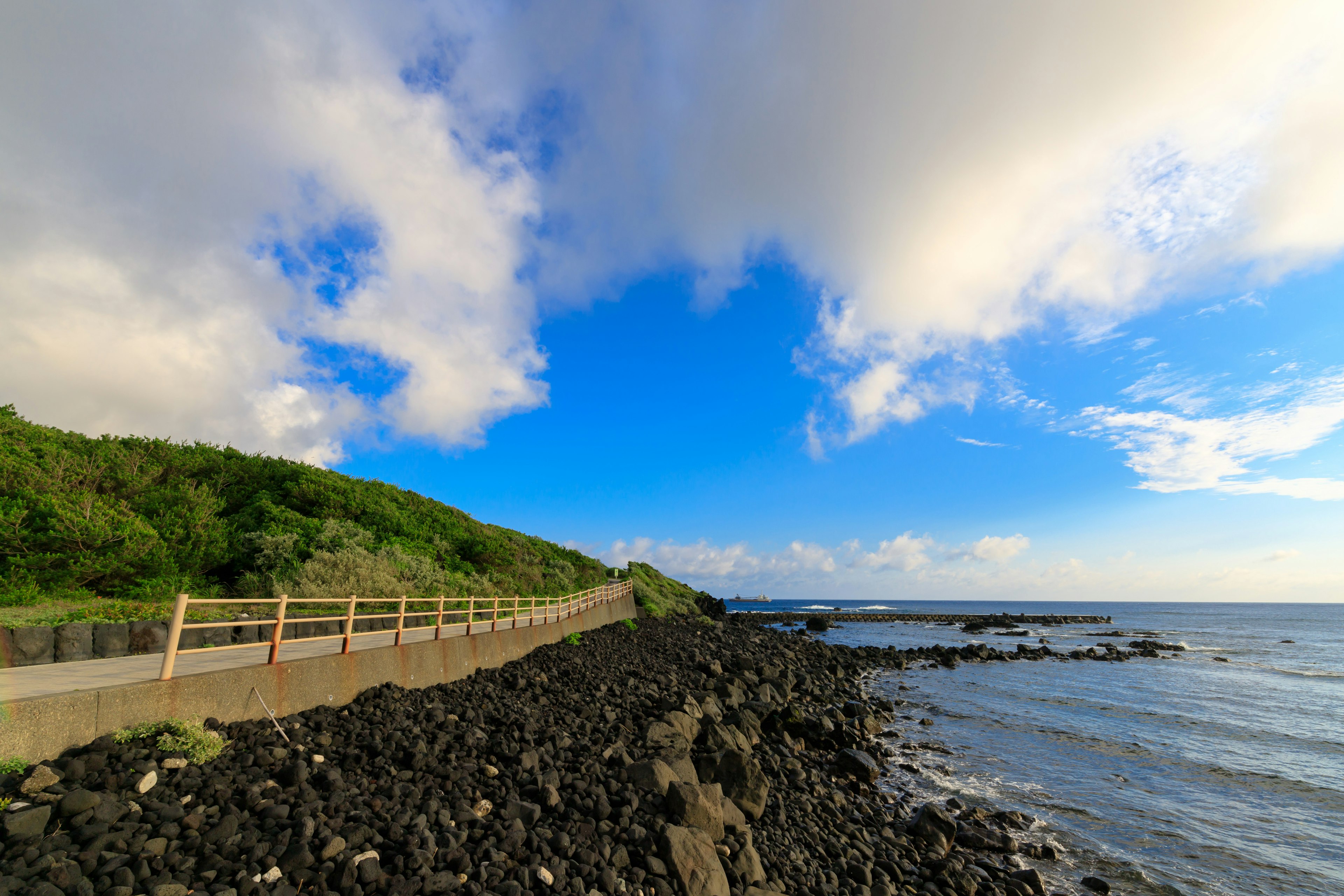 Küstenlandschaft mit blauem Himmel und weißen Wolken felsige Küste und Weg sichtbar