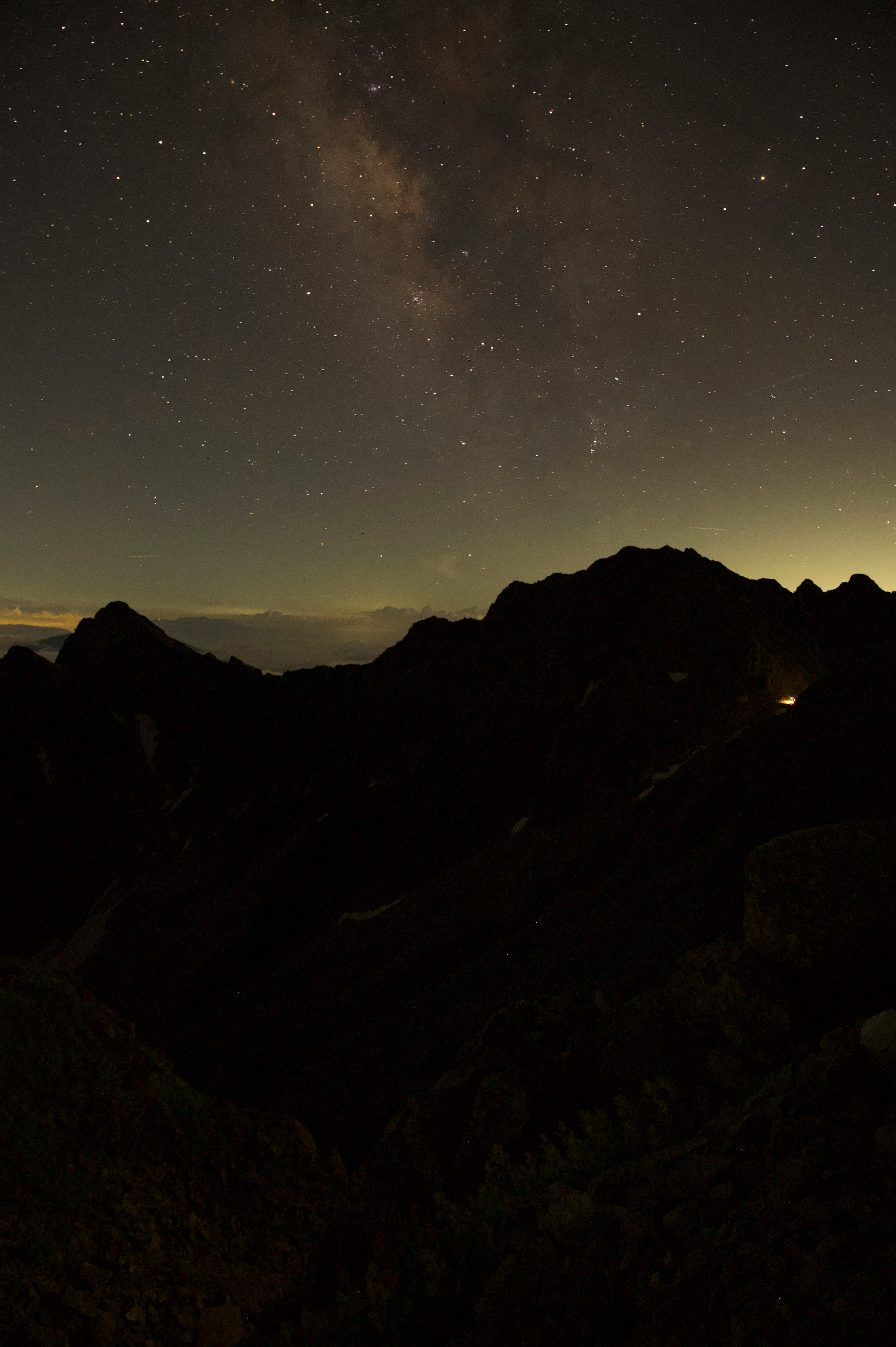 Night landscape featuring silhouettes of mountains under a starry sky