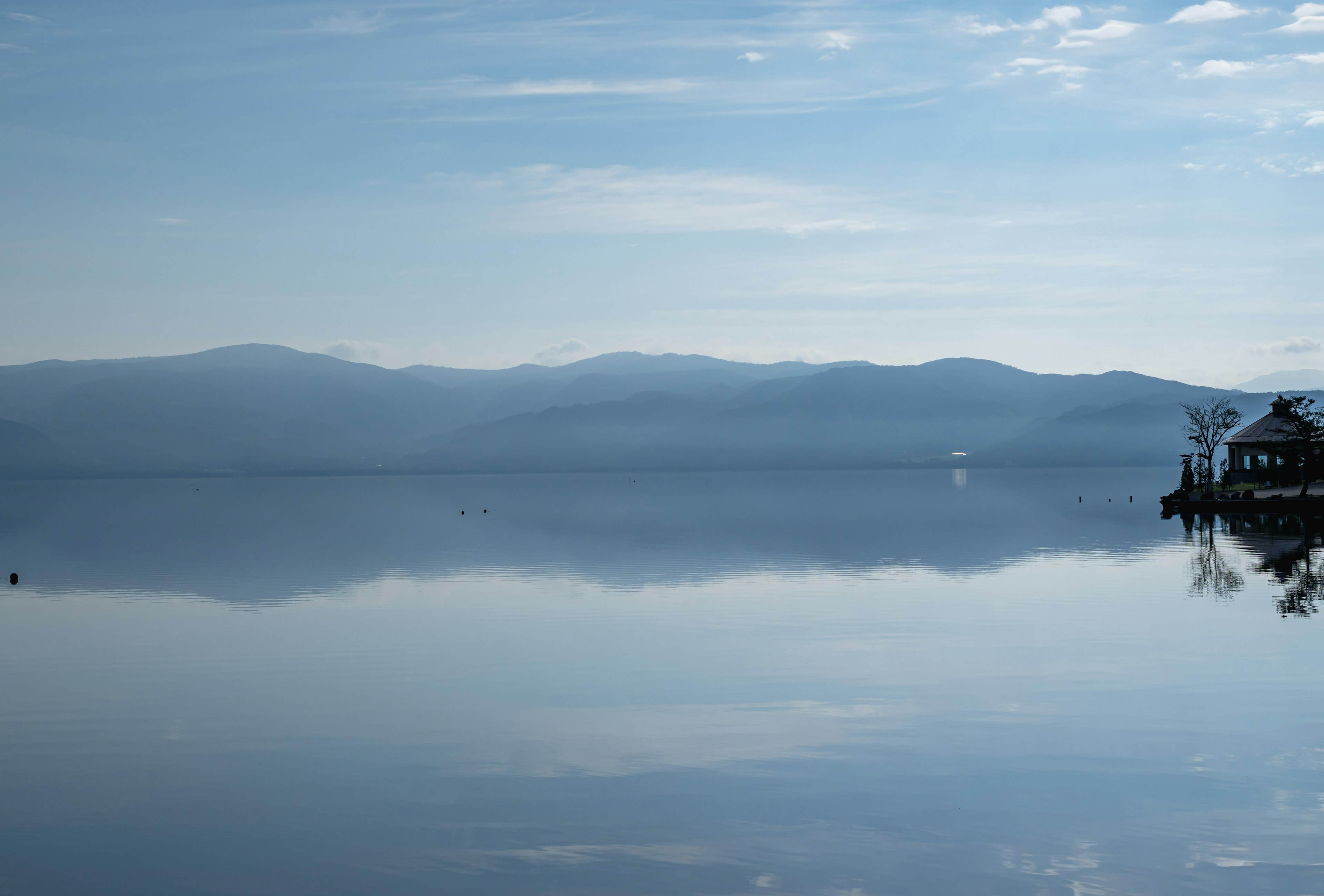 Ruhiger See, der Berge und blauen Himmel reflektiert