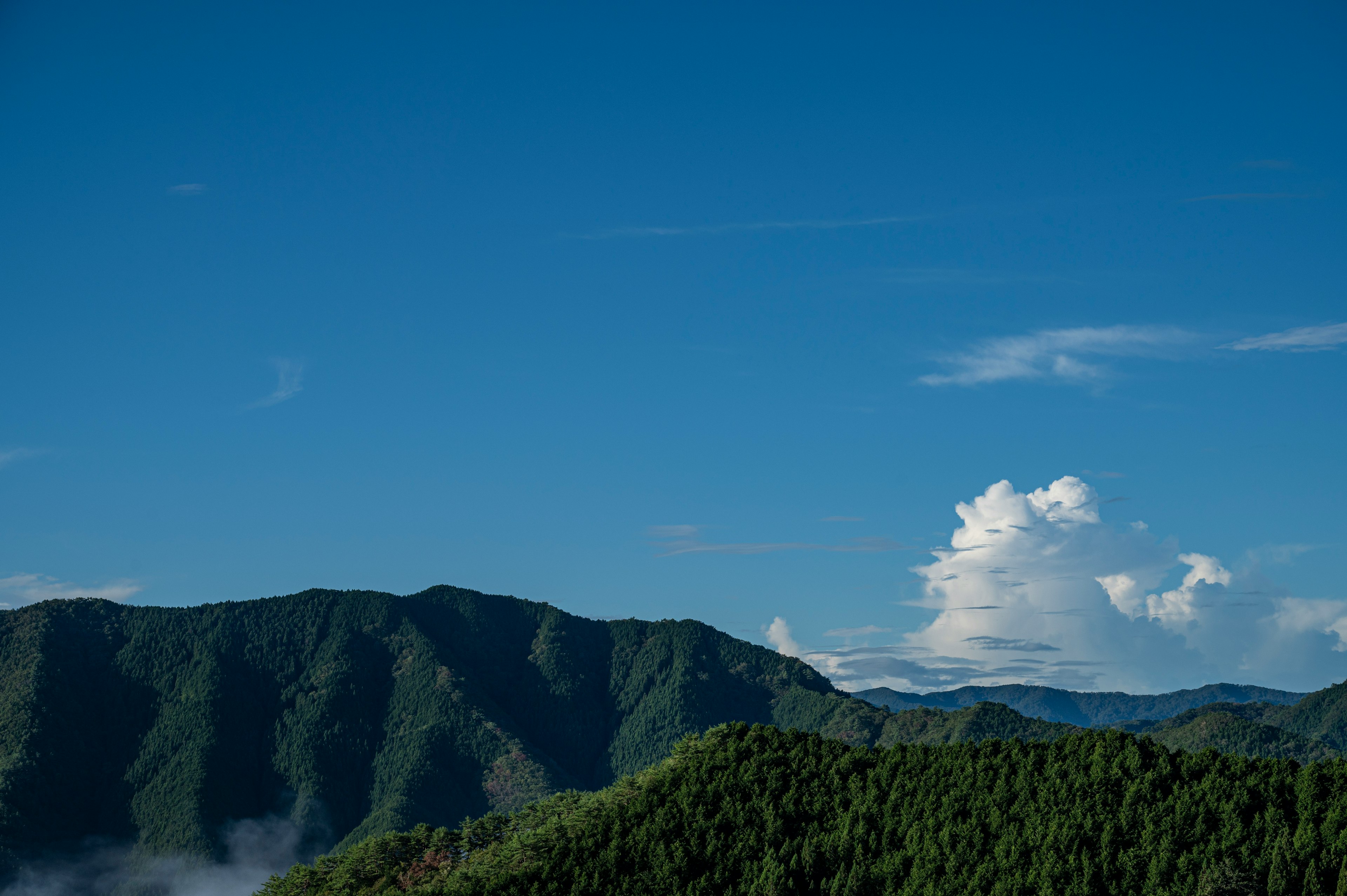 青空と白い雲が広がる山の風景