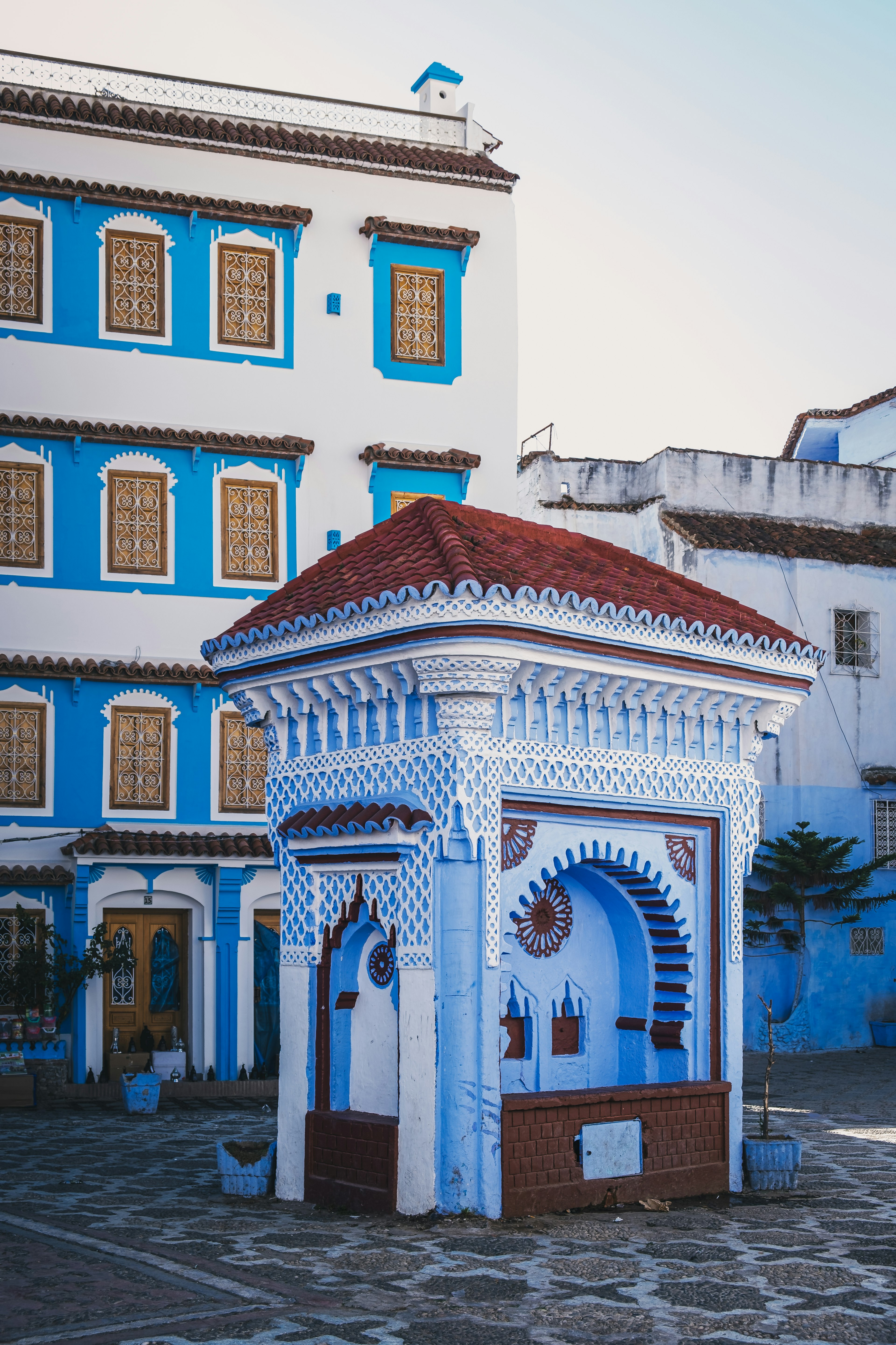 Decorative well in a square surrounded by blue and white buildings