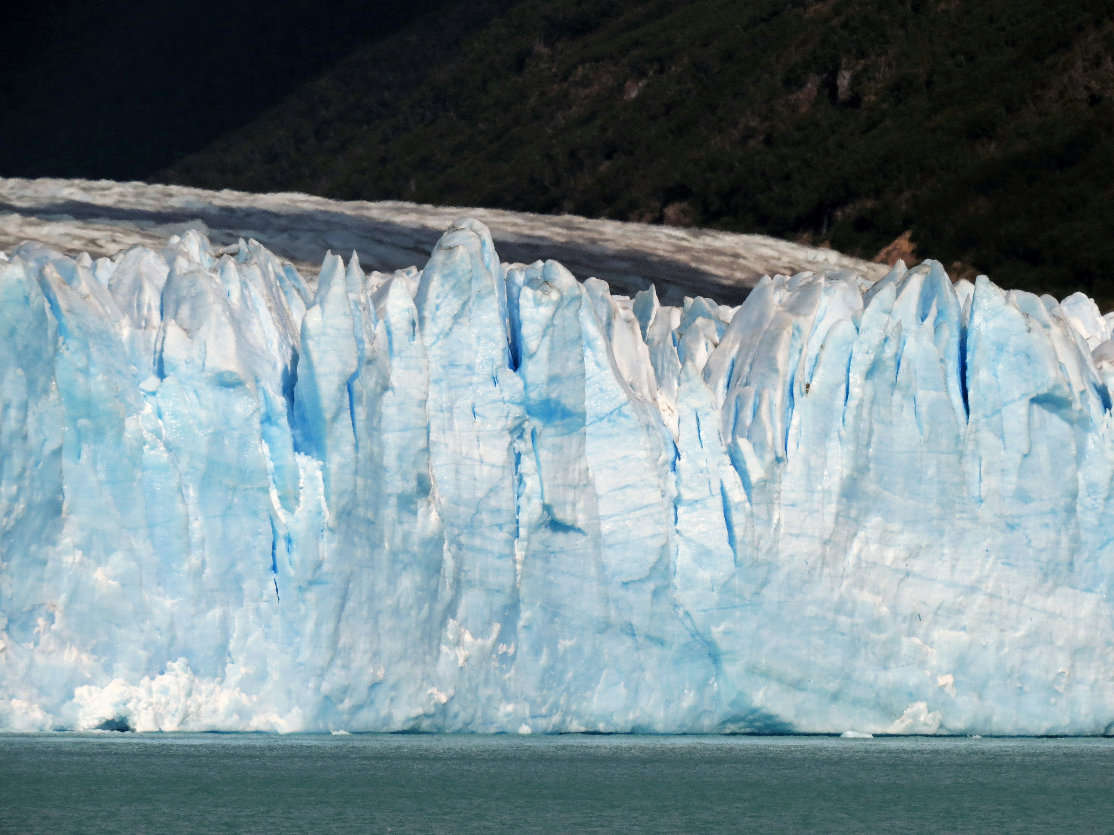 Impresionante pared de hielo azul de un glaciar reflejándose en la superficie del agua