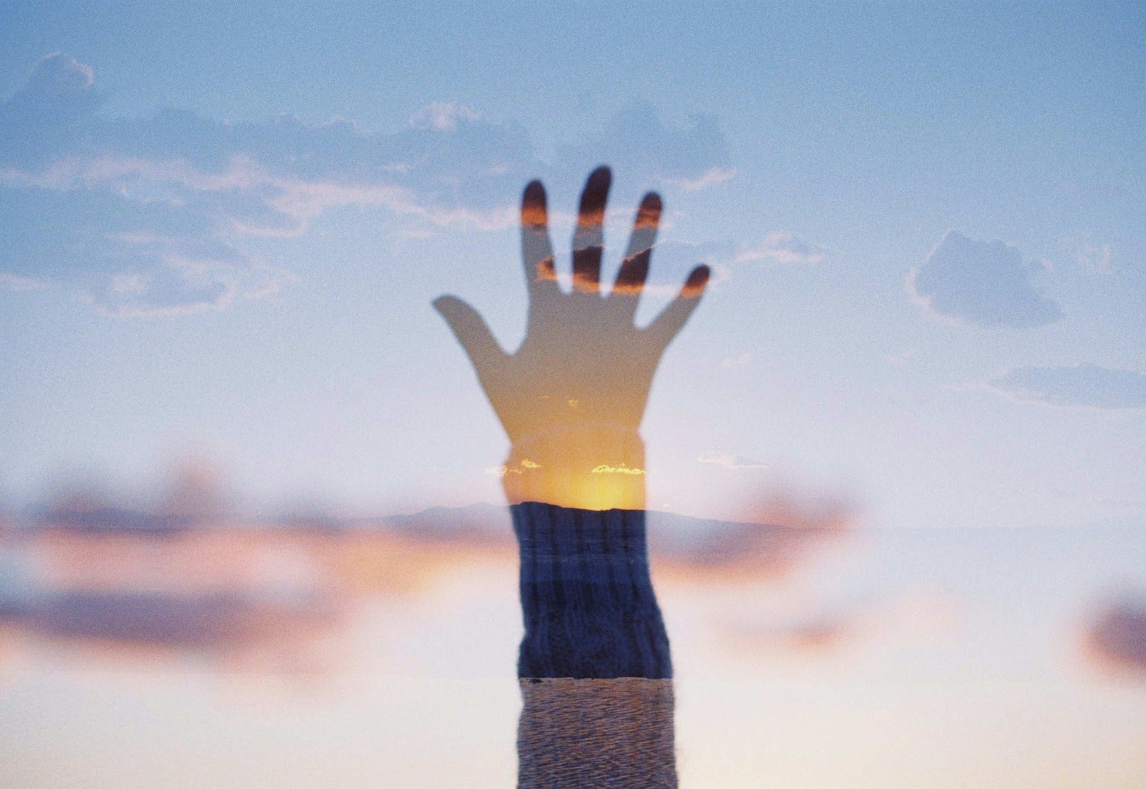 Silhouette di una mano che si alza verso il cielo