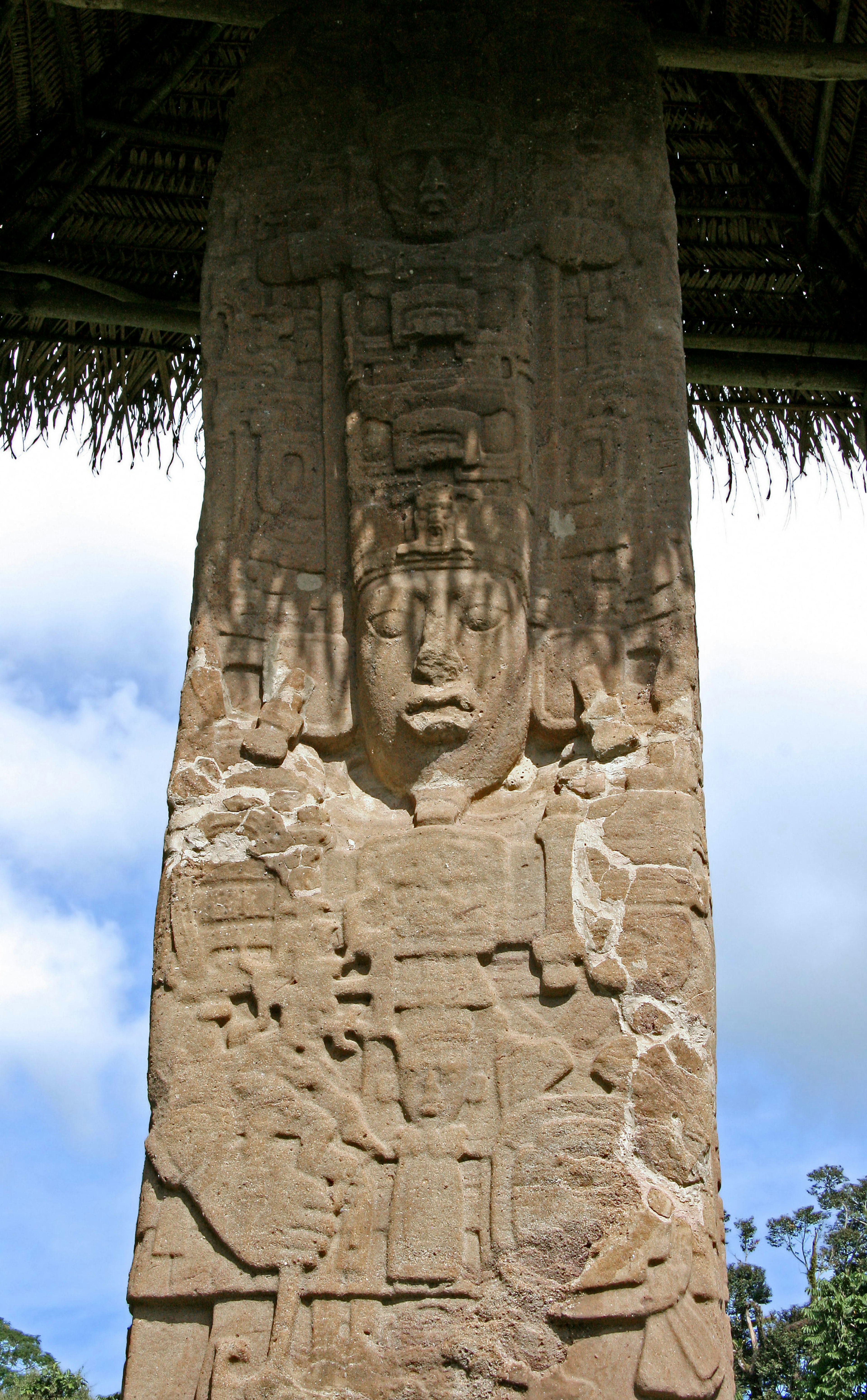 Ancient carved stone pillar with intricate designs and a mystical expression