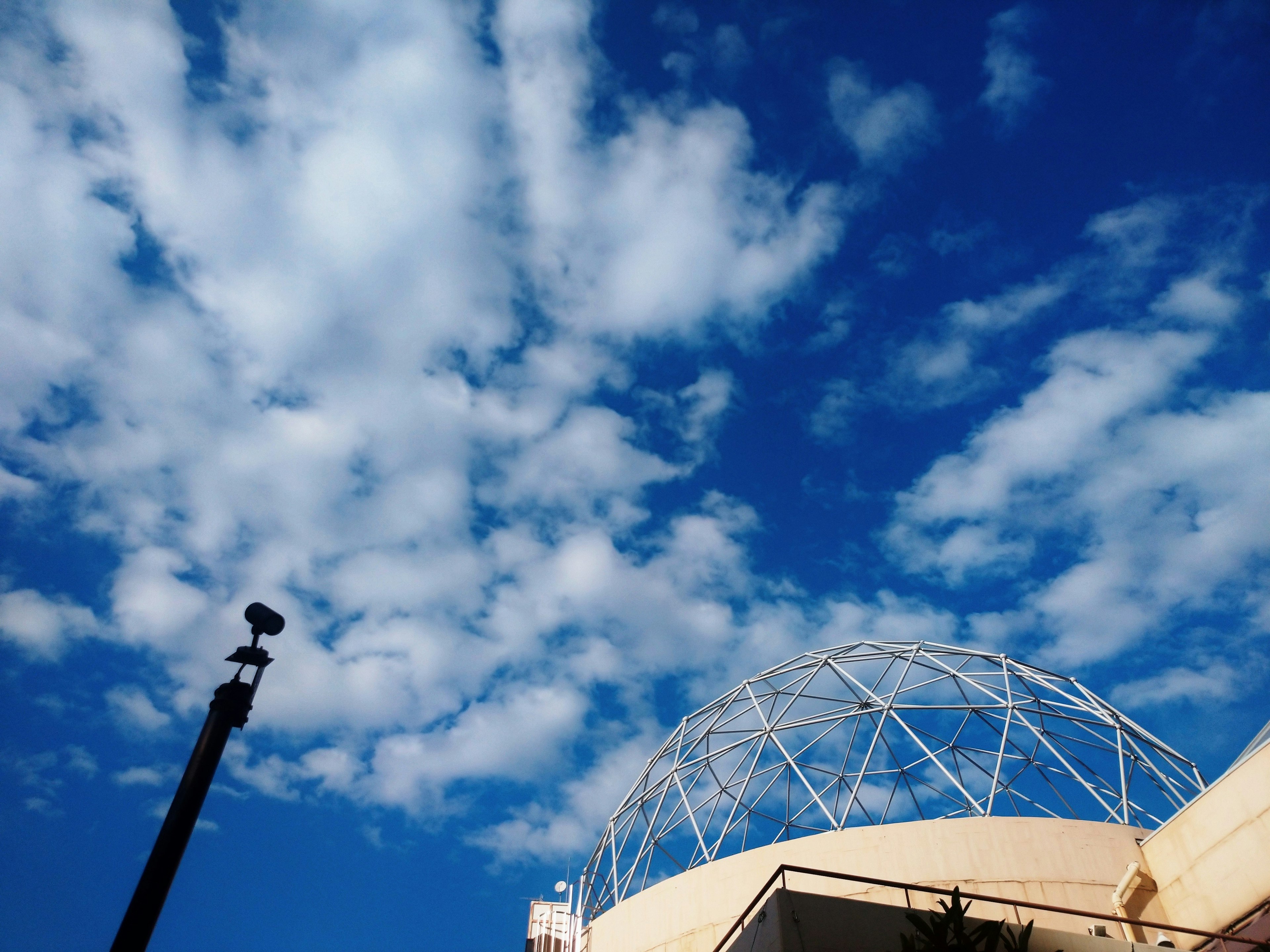 Nuages blancs dans un ciel bleu au-dessus d'un bâtiment en forme de dôme