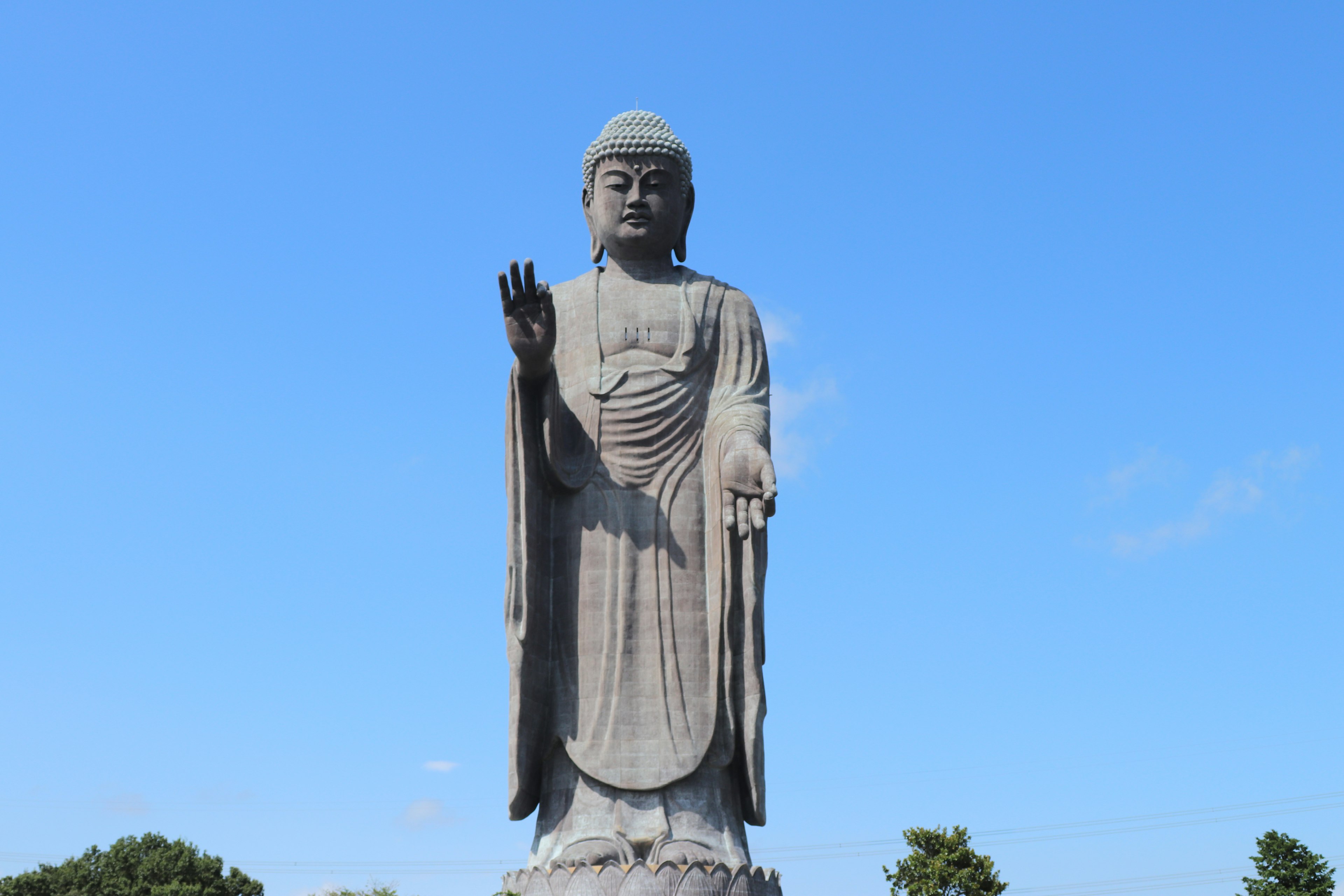 Full-body statue of a large Buddha under a blue sky