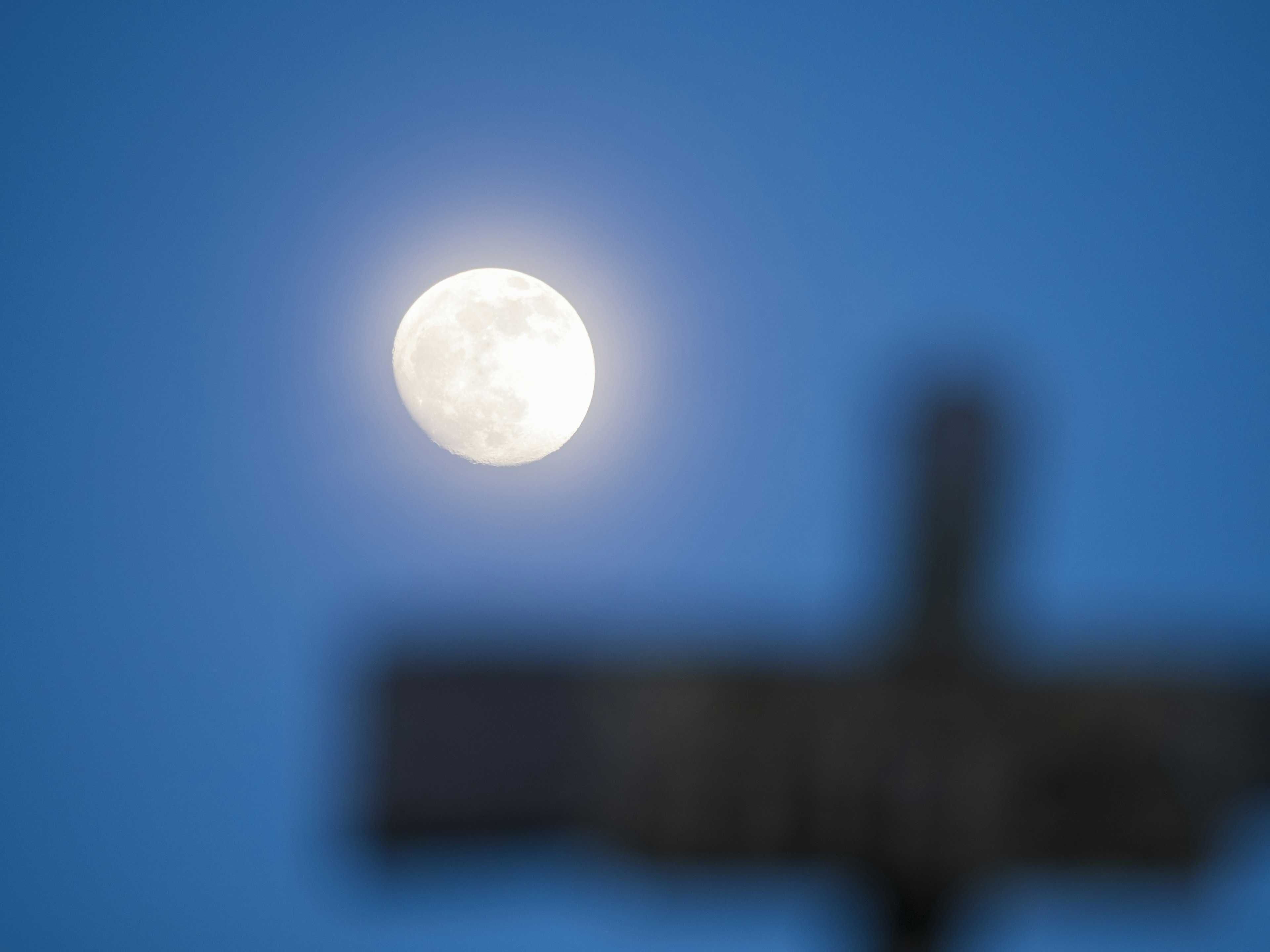 Full moon in a blue sky with a blurred sign in the foreground