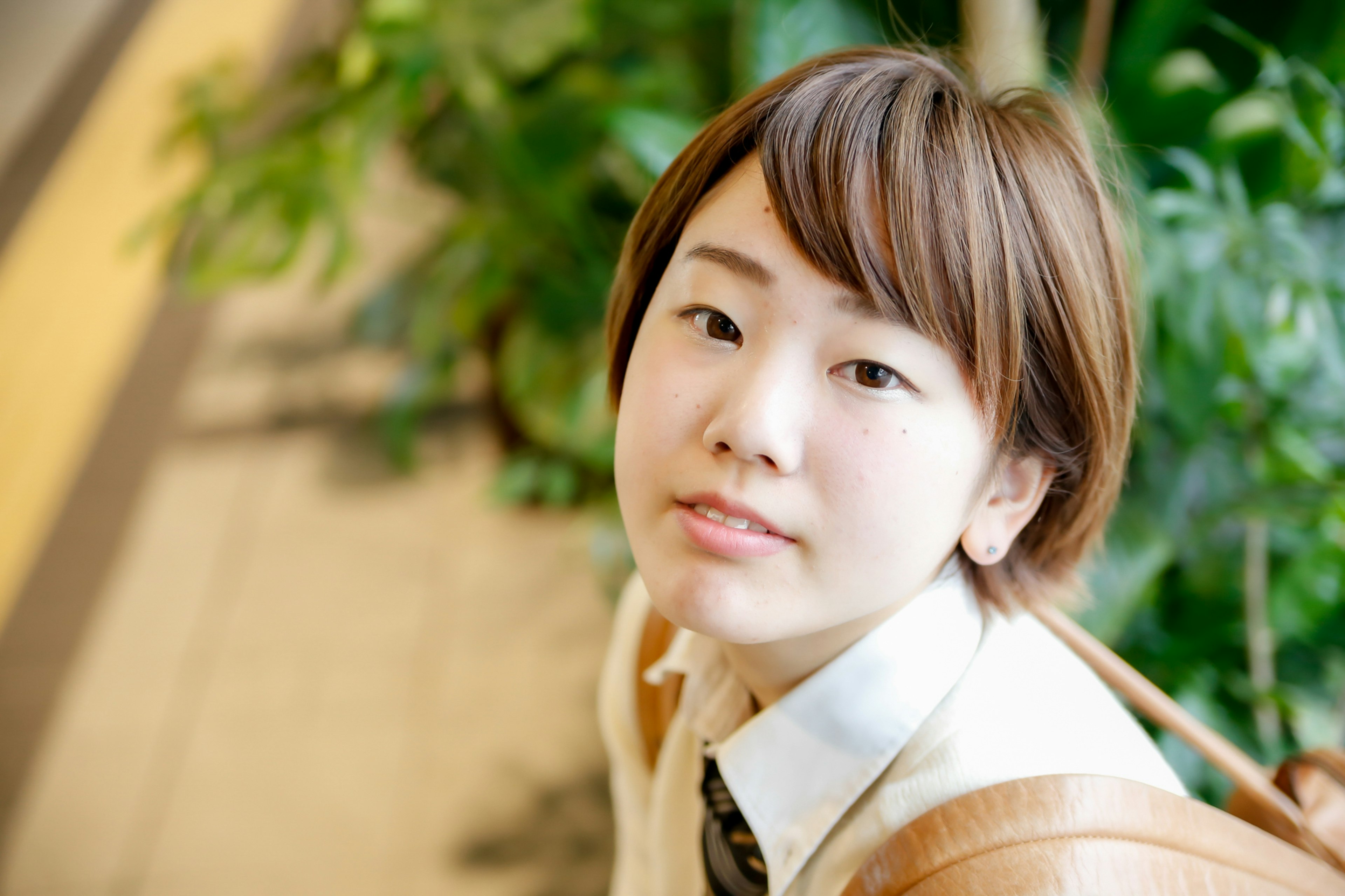 Jeune femme souriante devant des plantes Tenue décontractée avec une expression naturelle