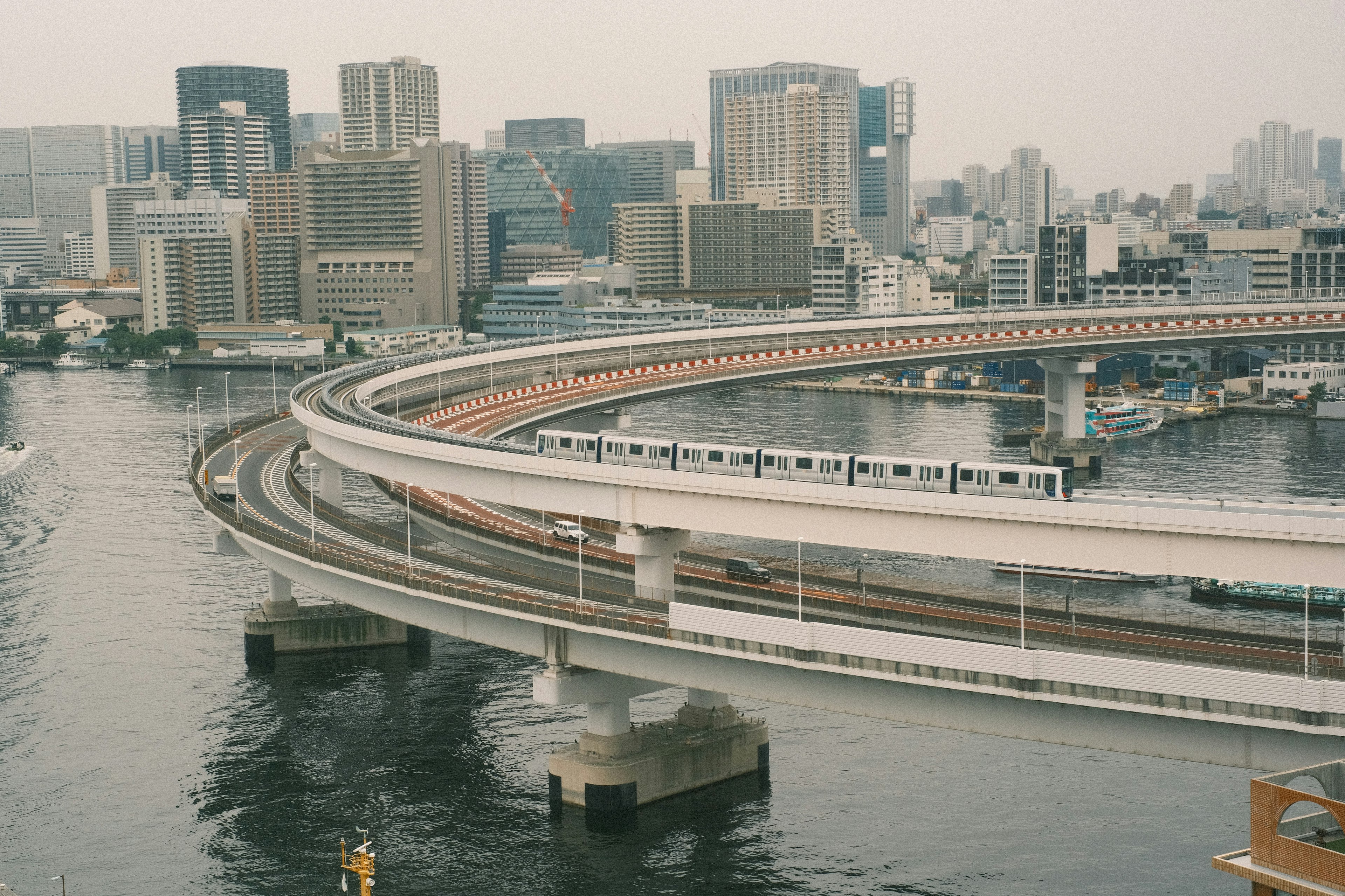 Hochbahn, die durch das Tokyo-Bay-Gebiet mit Stadtsilhouette fährt