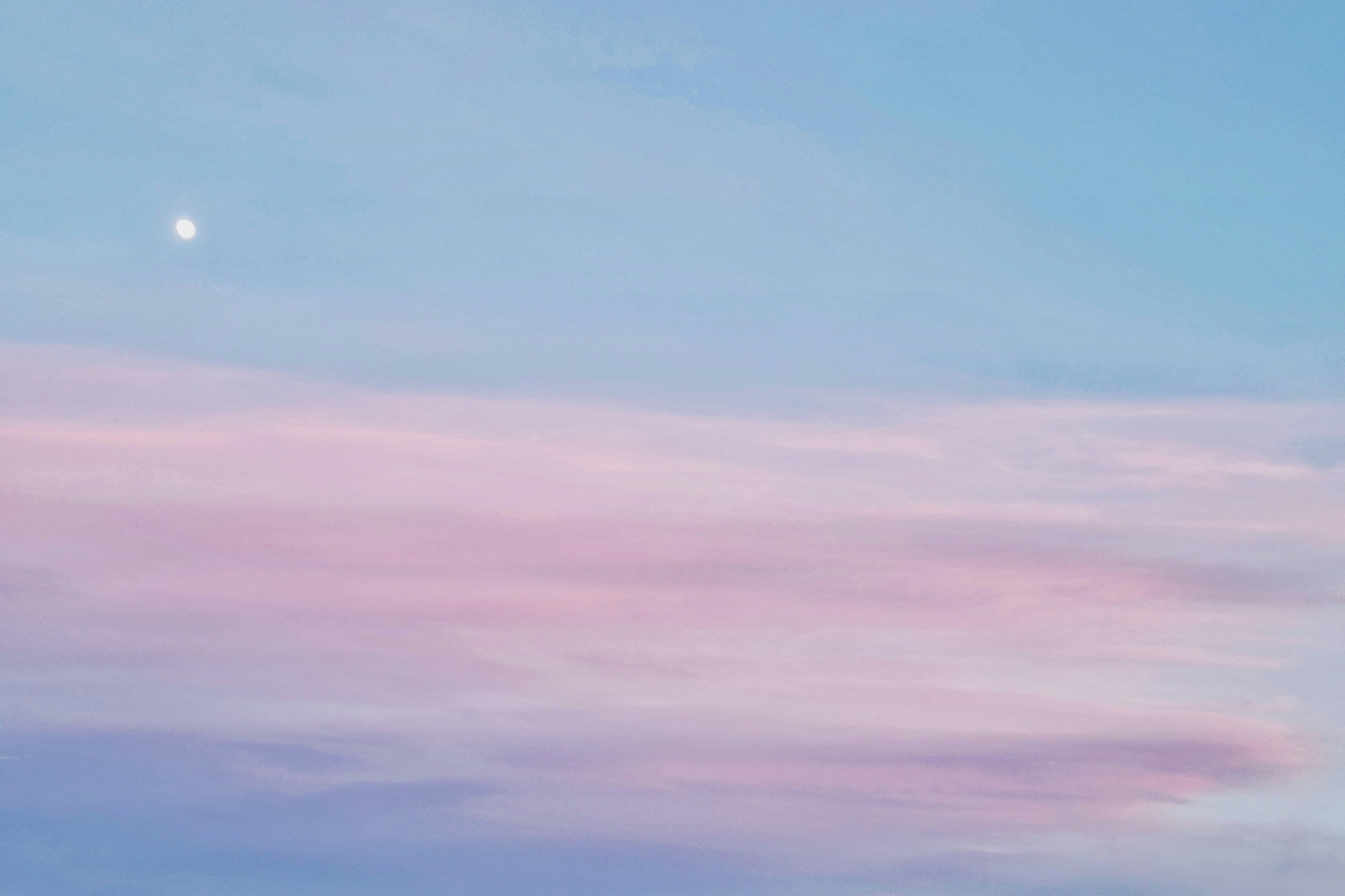 Ein sanfter blauer und rosa Himmel mit einem kleinen Mond sichtbar