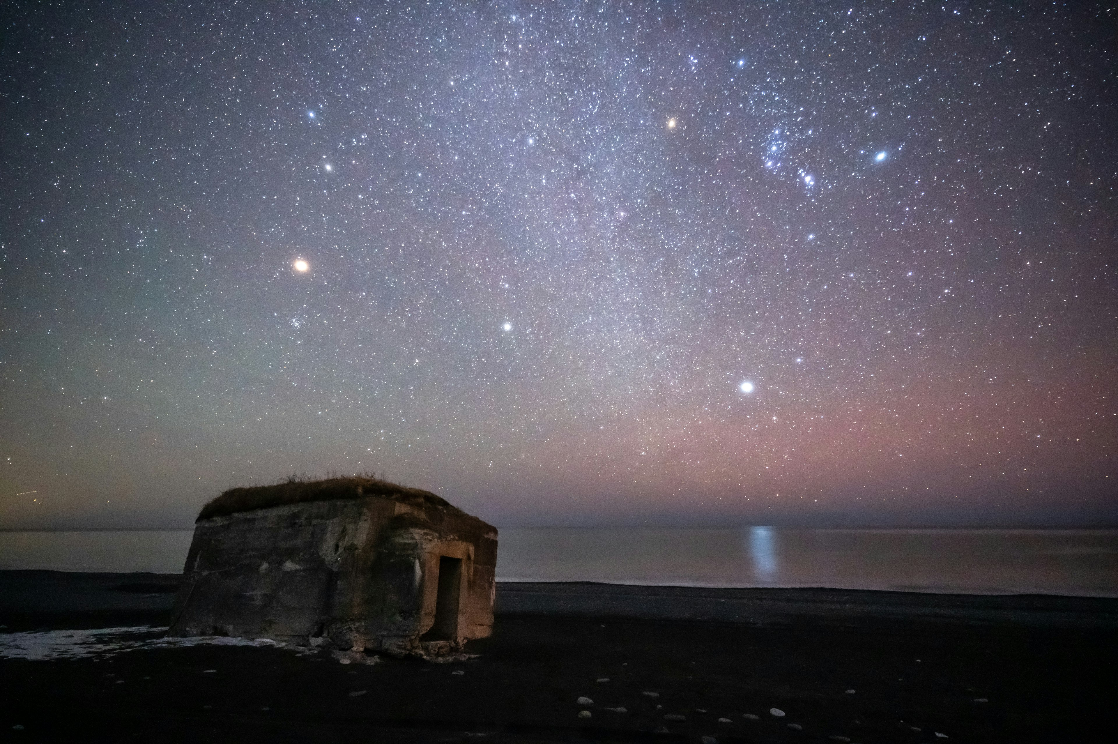 星空の下にある古い小屋と海の風景