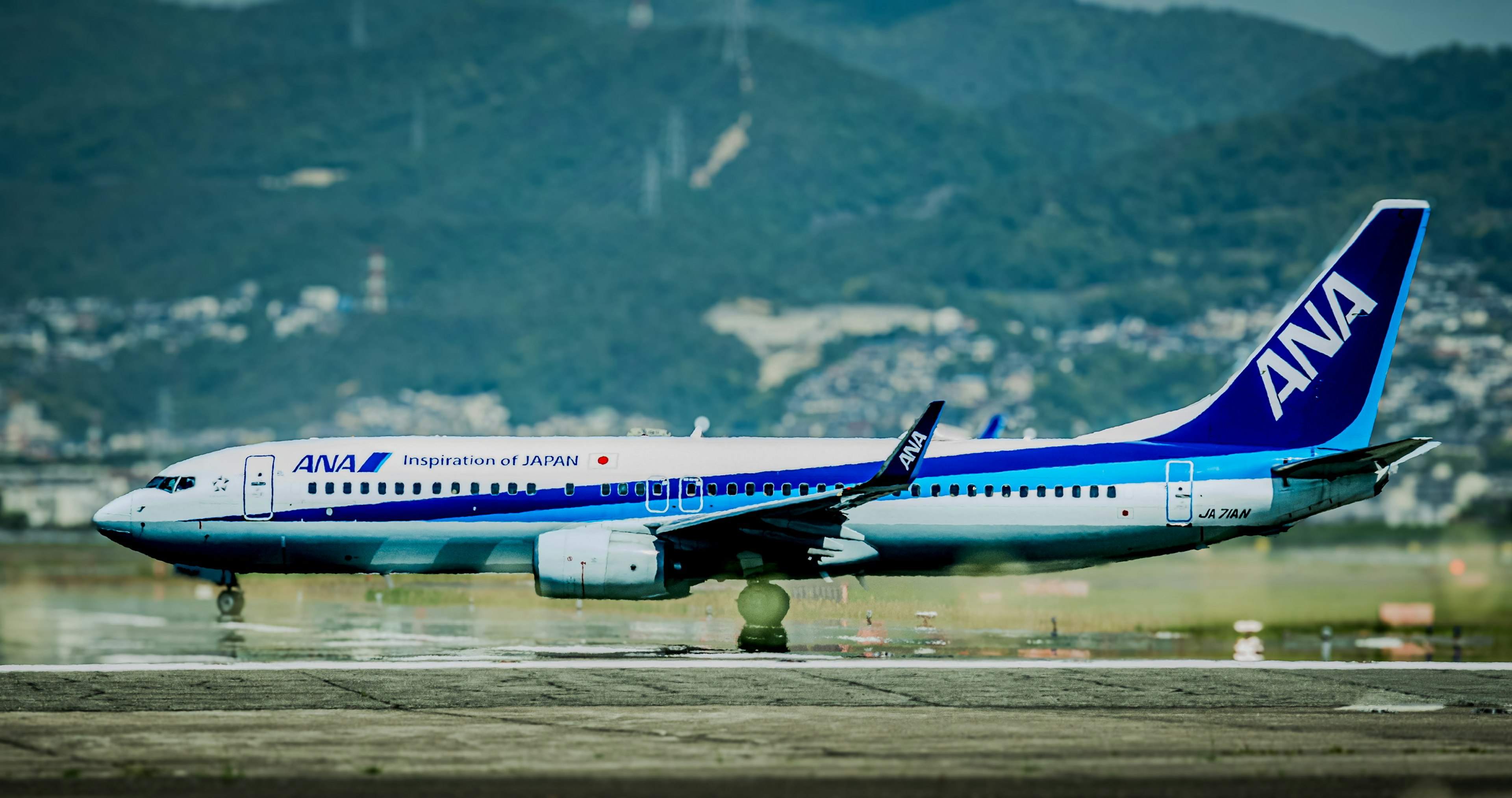 ANA airplane on the runway with mountains in the background