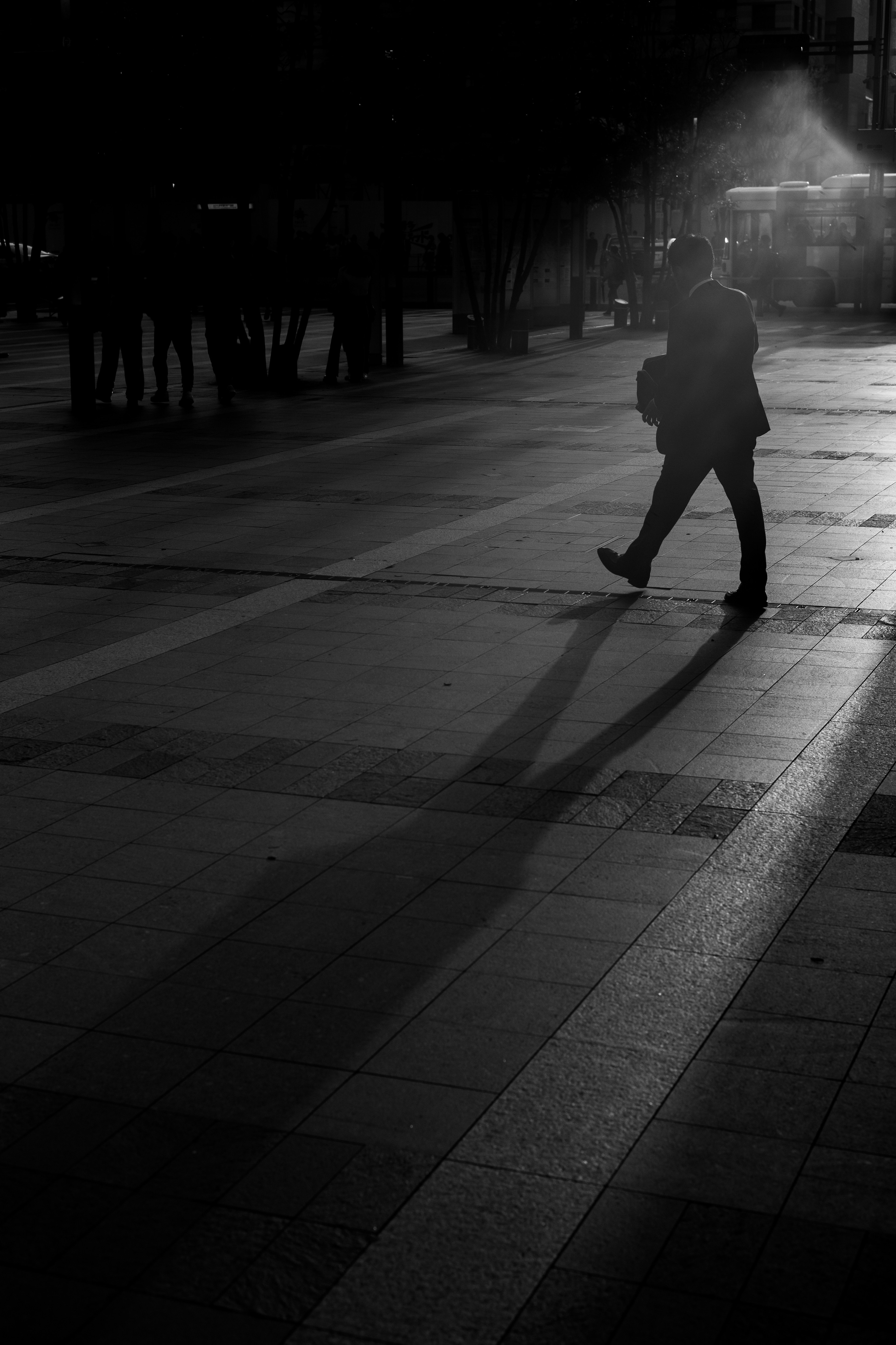 Silhouette d'une personne marchant dans un cadre urbain sombre avec de longues ombres