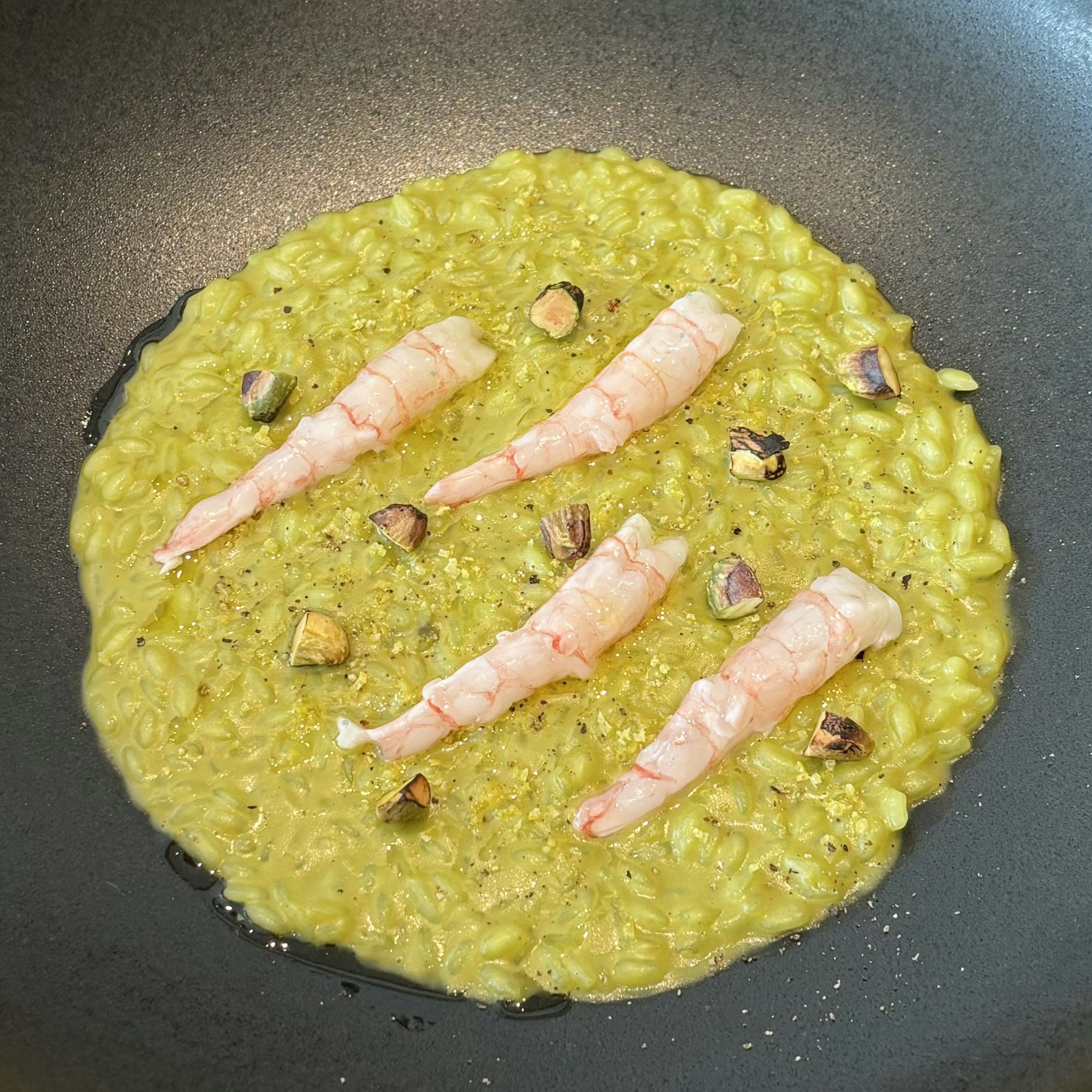 Green risotto topped with shrimp and pistachios