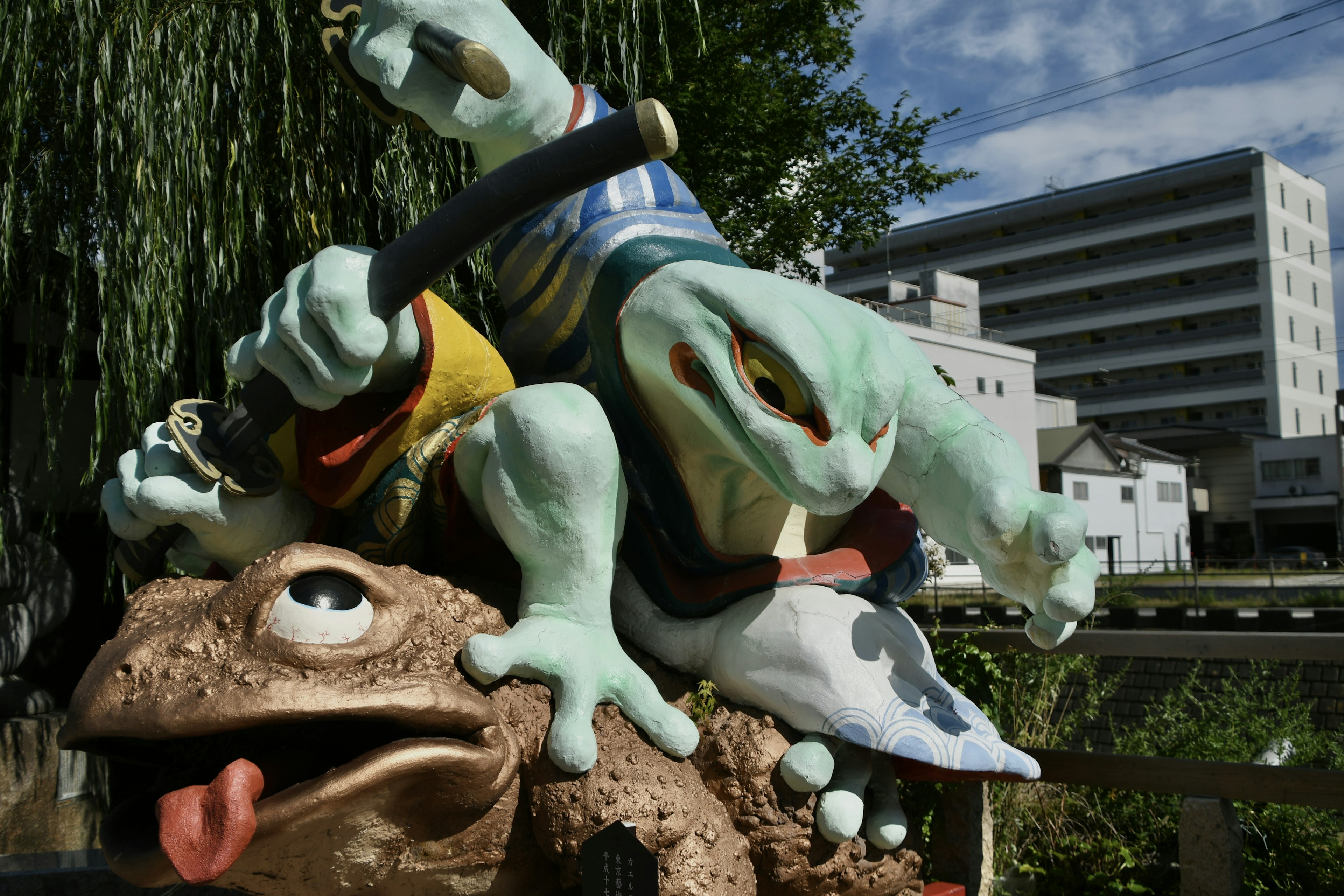 Un personaggio verde con una spada seduto su una scultura di rana