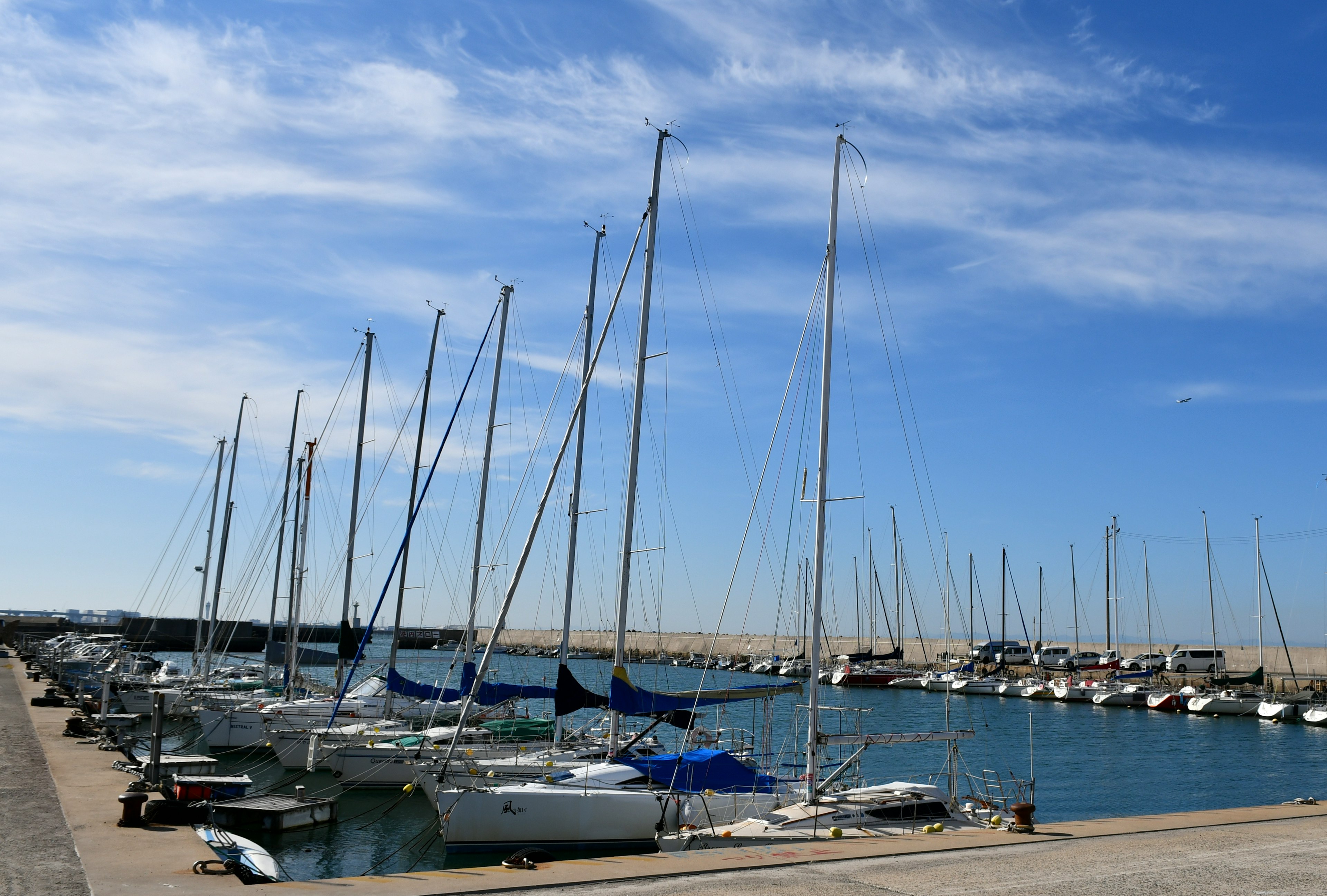 Yachts lined up in a serene harbor under a blue sky