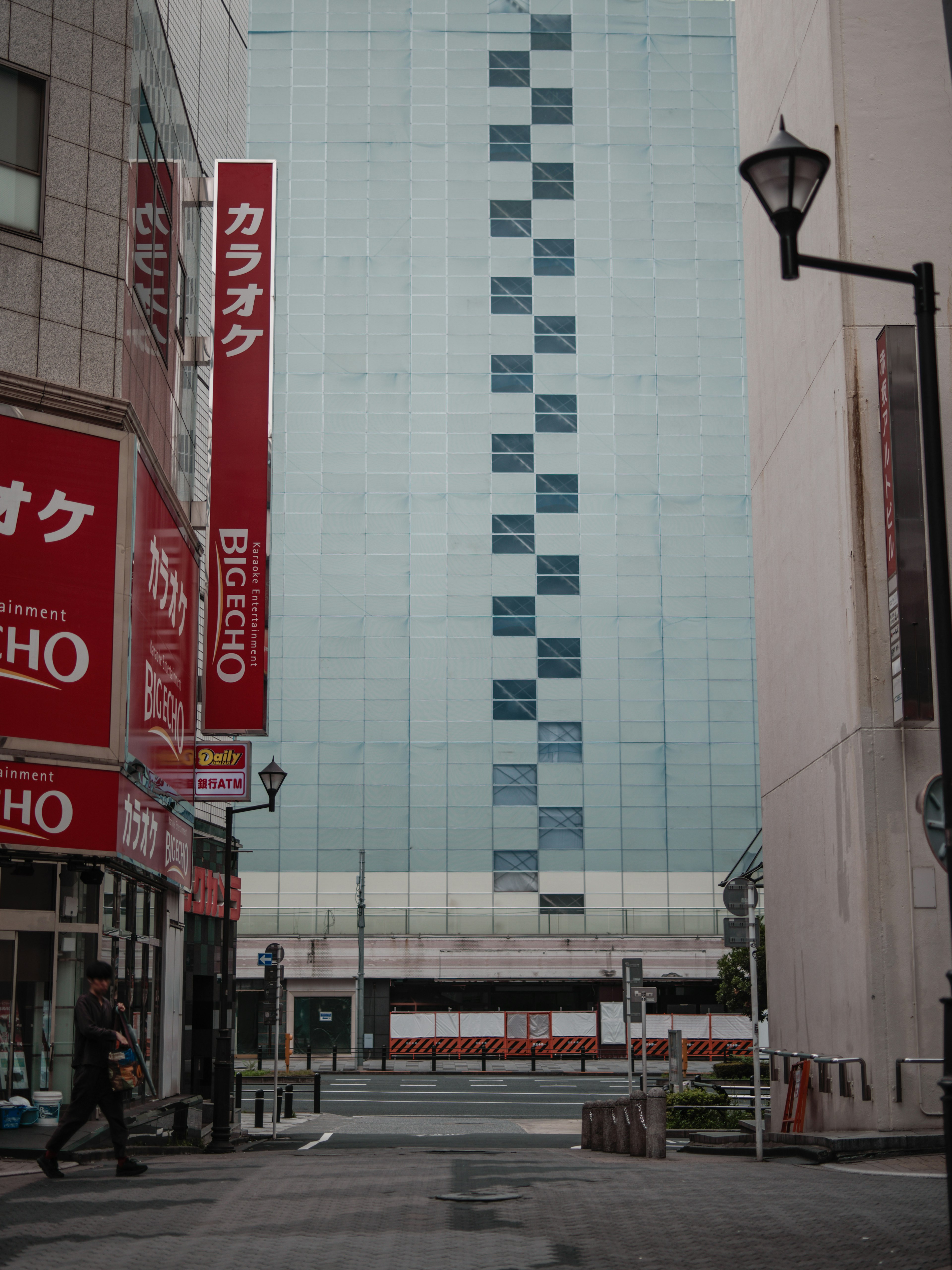 Vue de rue avec un bâtiment en verre bleu et des panneaux rouges