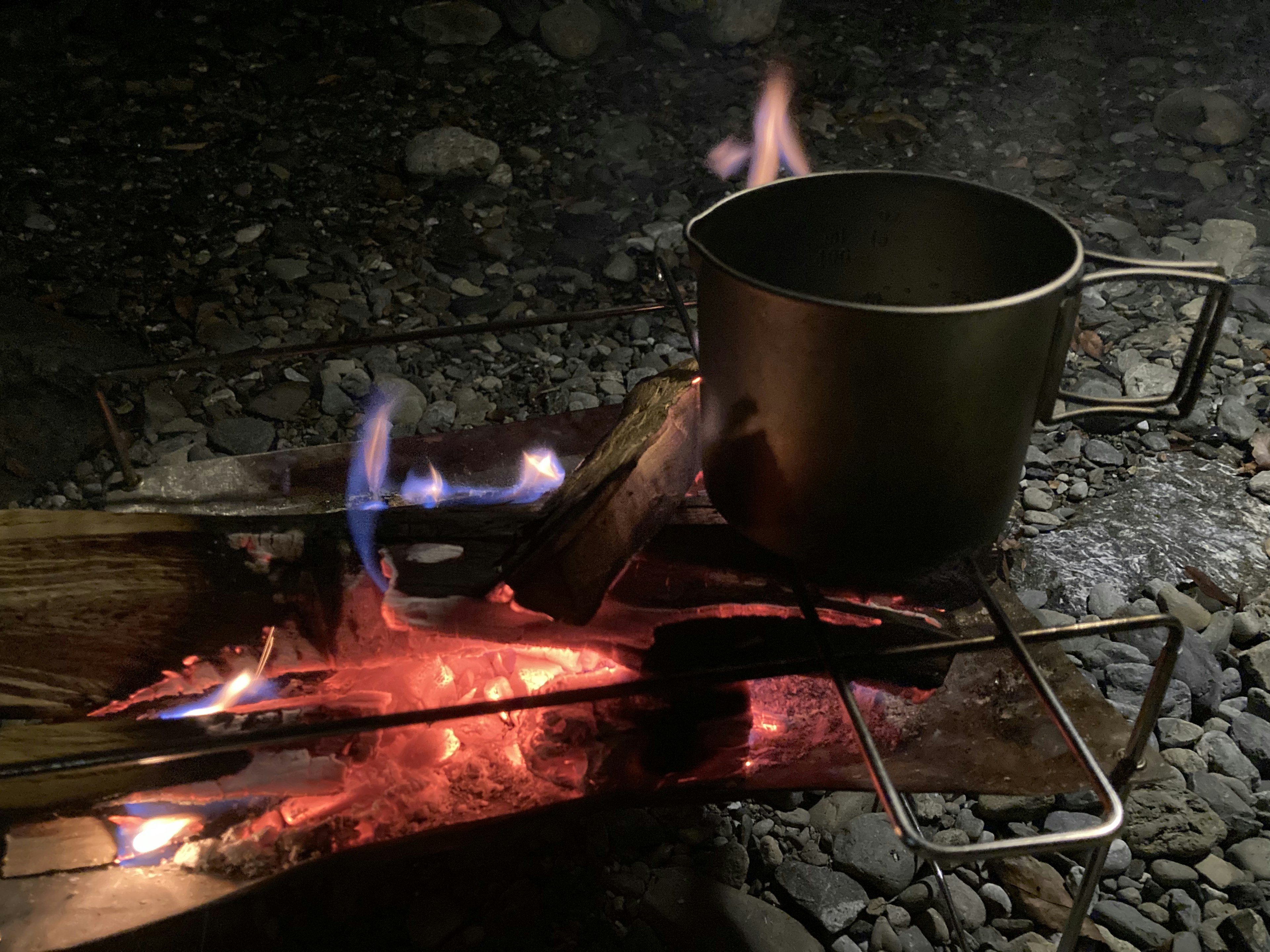 Casserole en métal sur un feu de camp avec des flammes et des braises