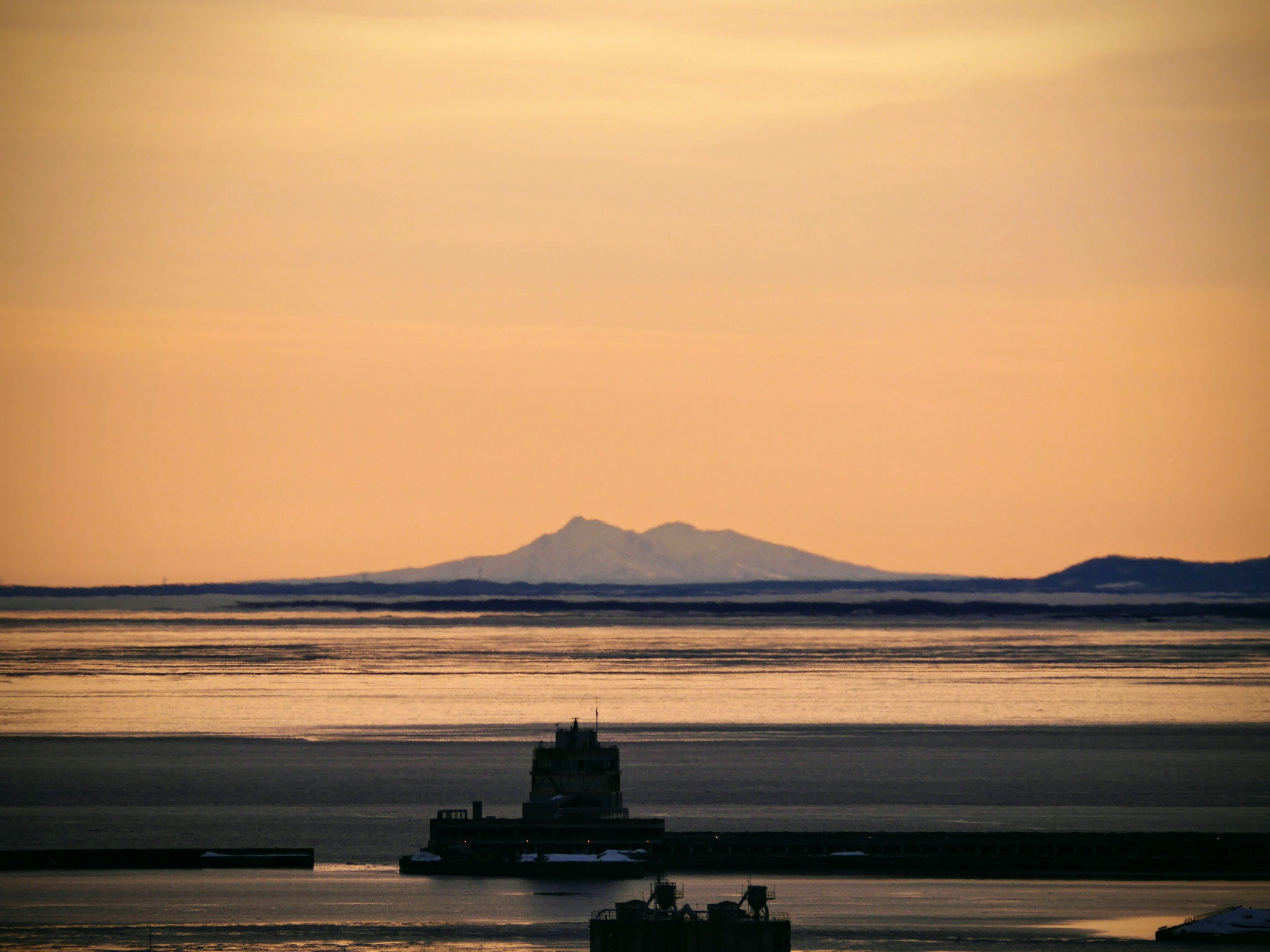 夕暮れの海を背景にした遠くの山々と船のシルエット