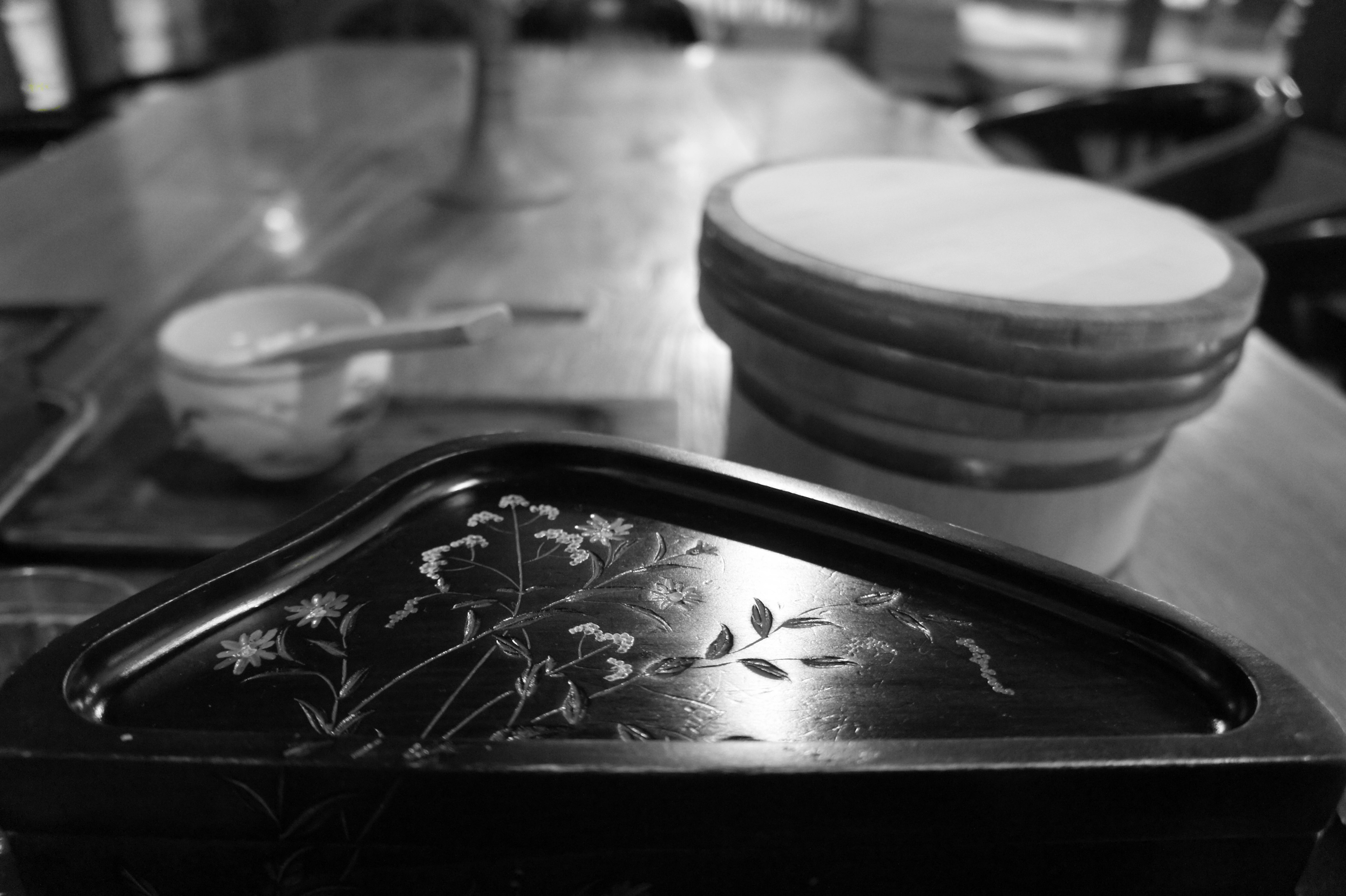 Plateau noir avec motif floral à côté de plats blancs sur une table en bois