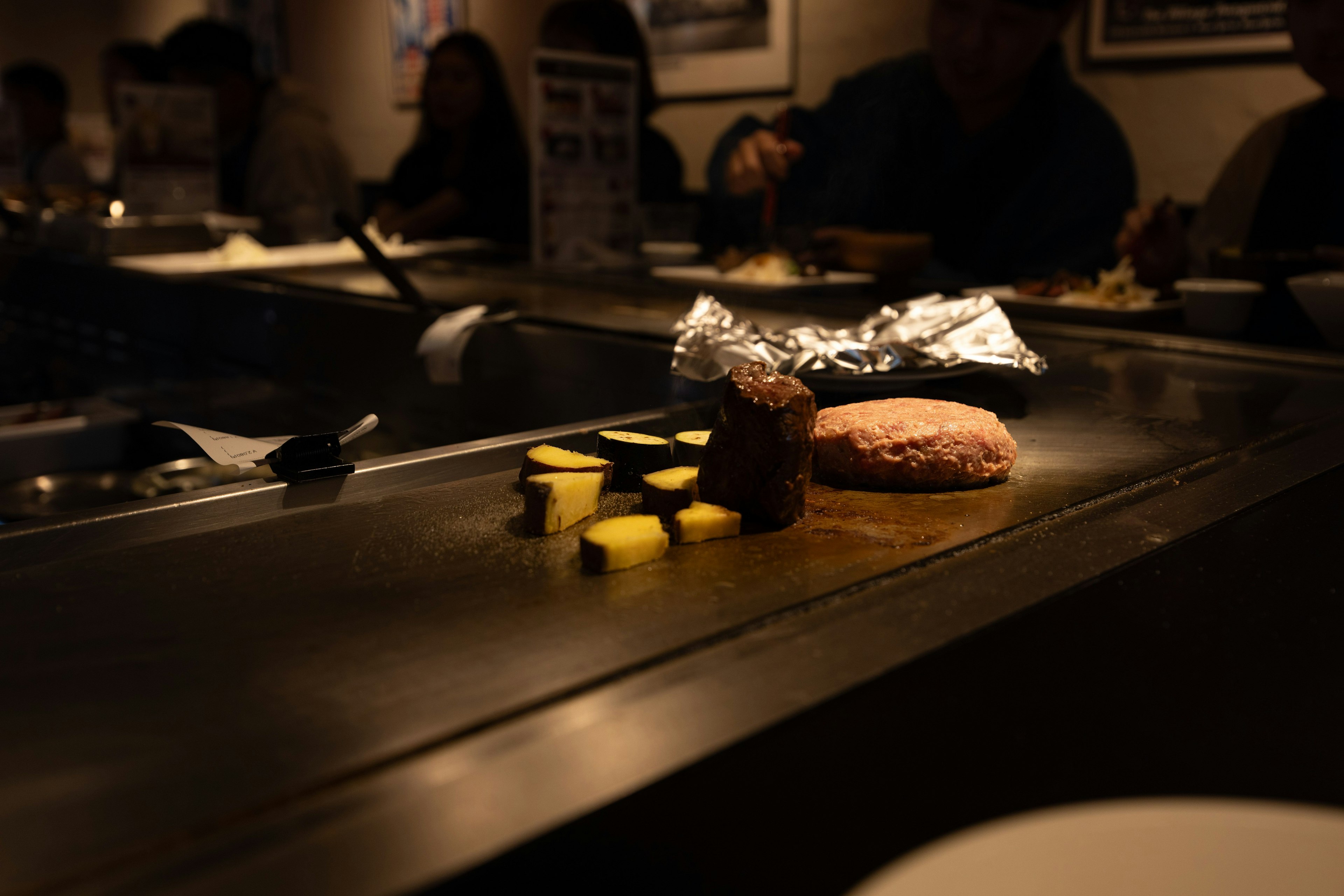 Gegrilltes Gemüse und Hamburger-Pattie auf einem Teppanyaki-Grill