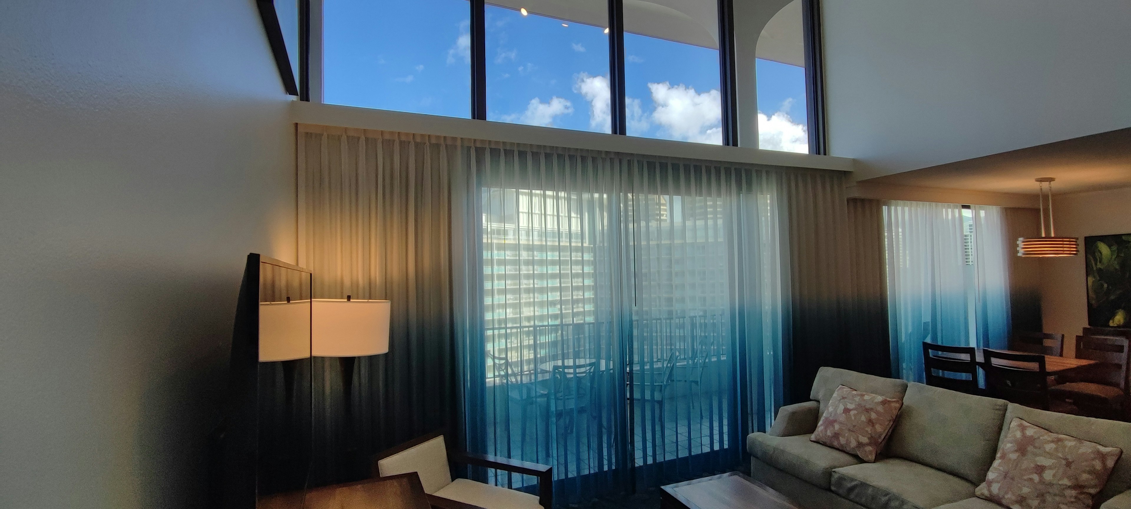 Sala luminosa con grandes ventanas que muestran cielo azul y nubes