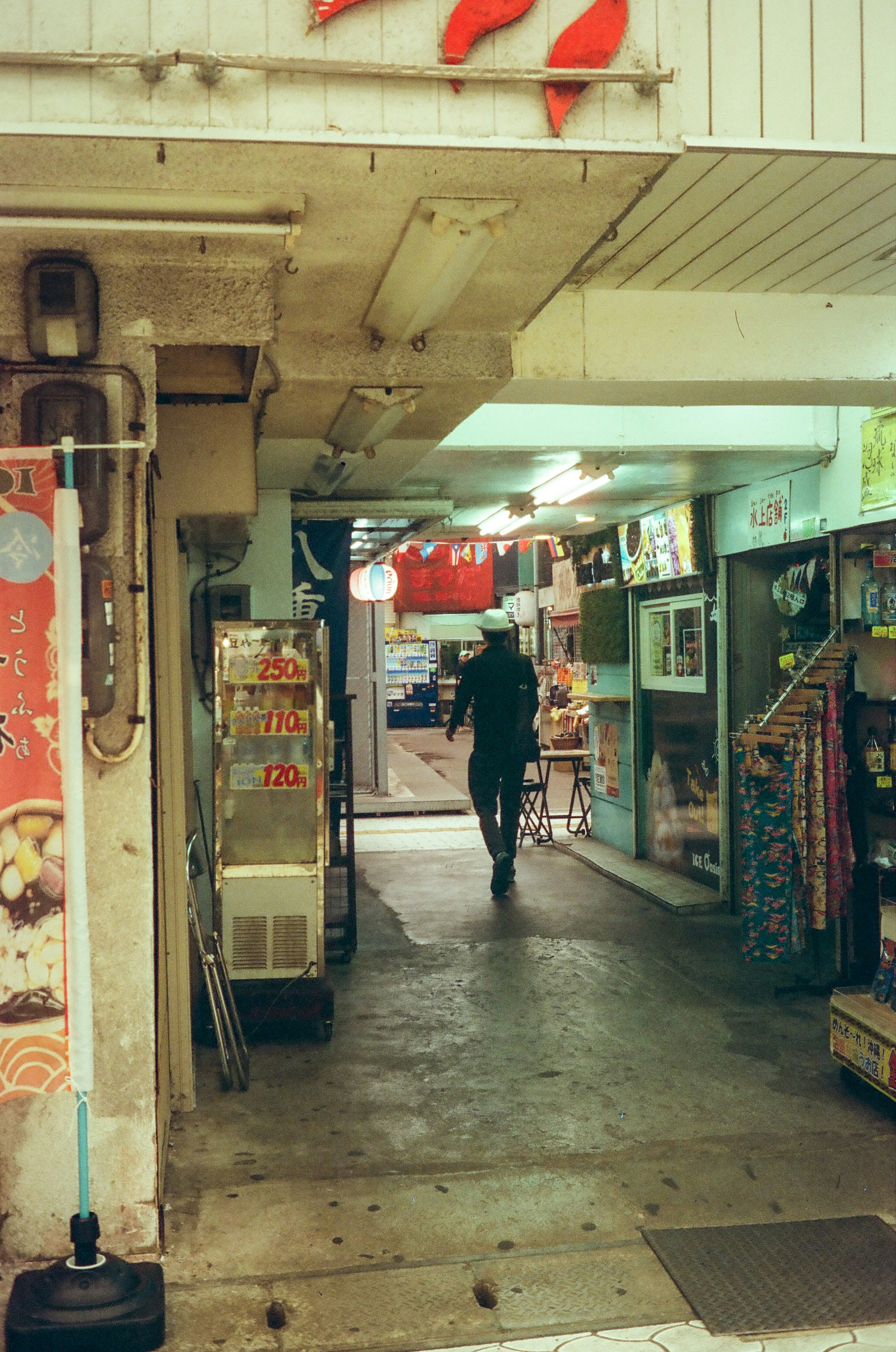 狭い通路を歩く人物が見える商店街の風景