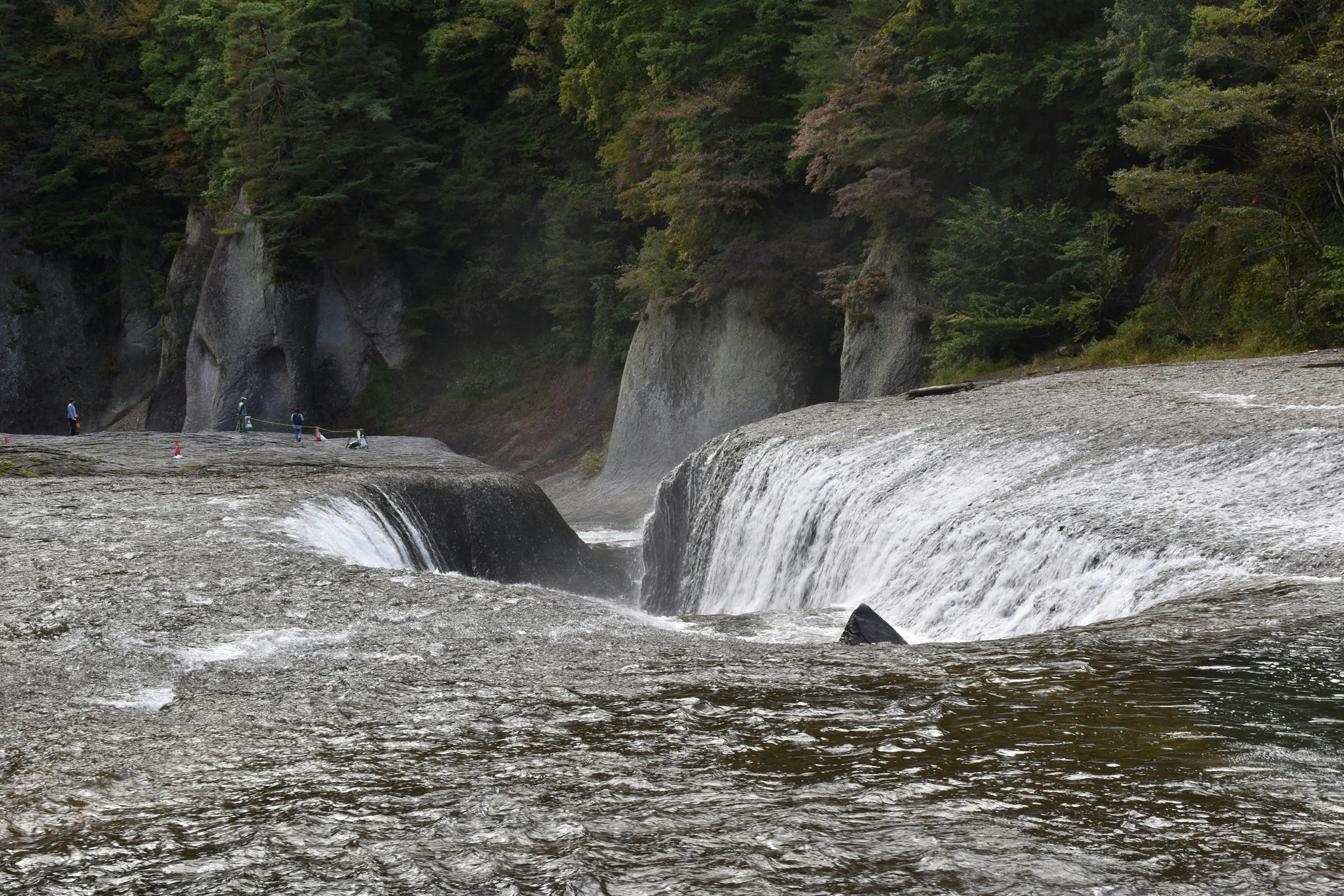 Ruhige Flusslandschaft mit einem schönen Wasserfall umgeben von grünen Bäumen