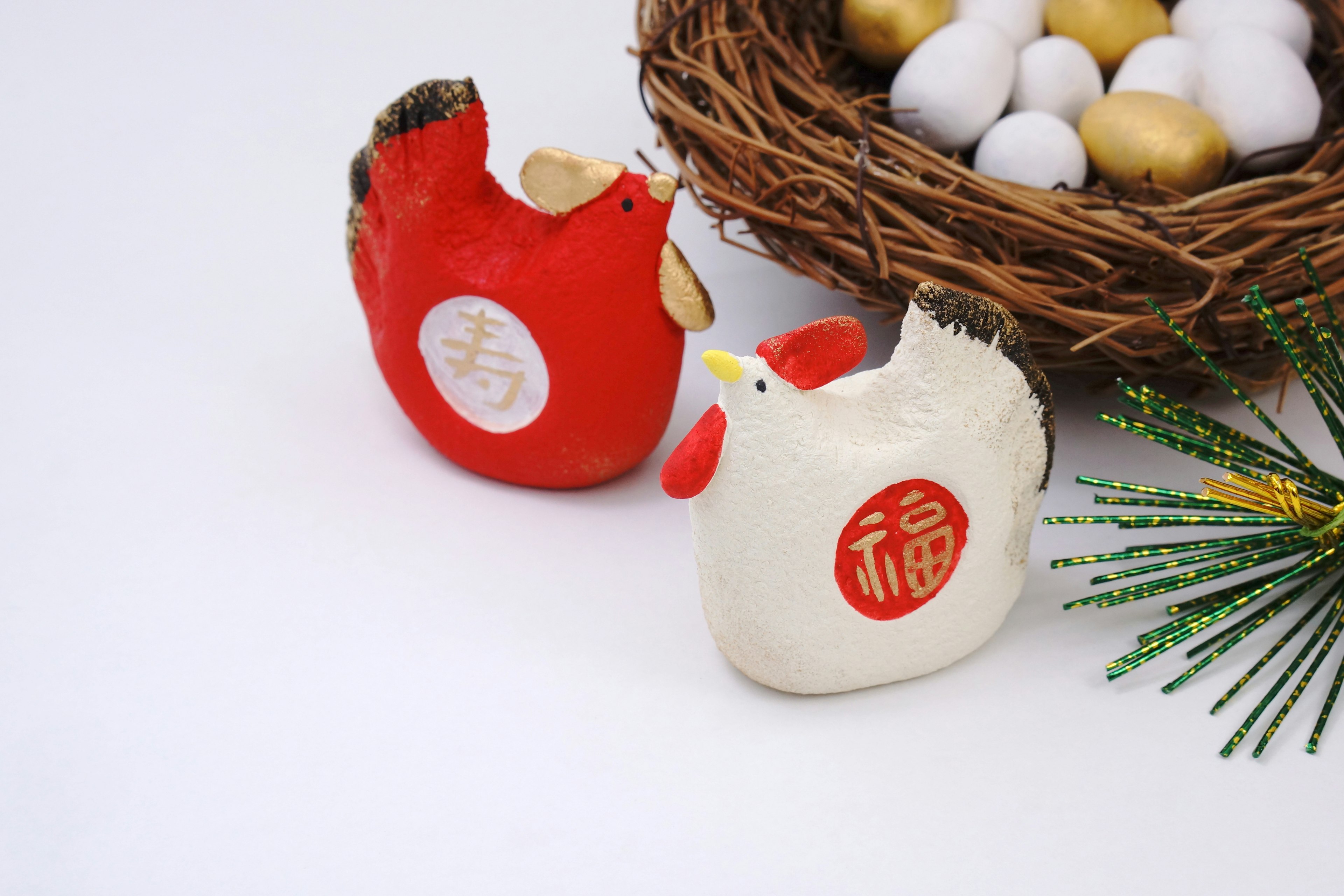 Red and white chicken figurines beside a nest filled with eggs