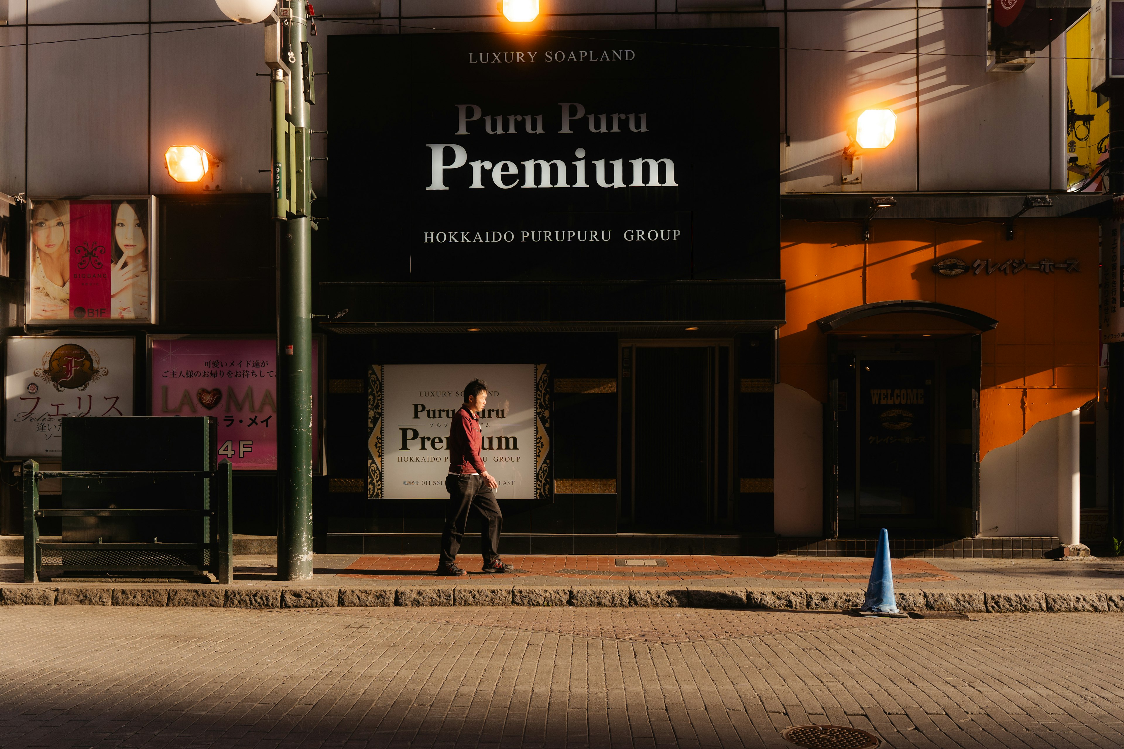 夜の街角に立つPuru Puru Premiumの看板と人通り