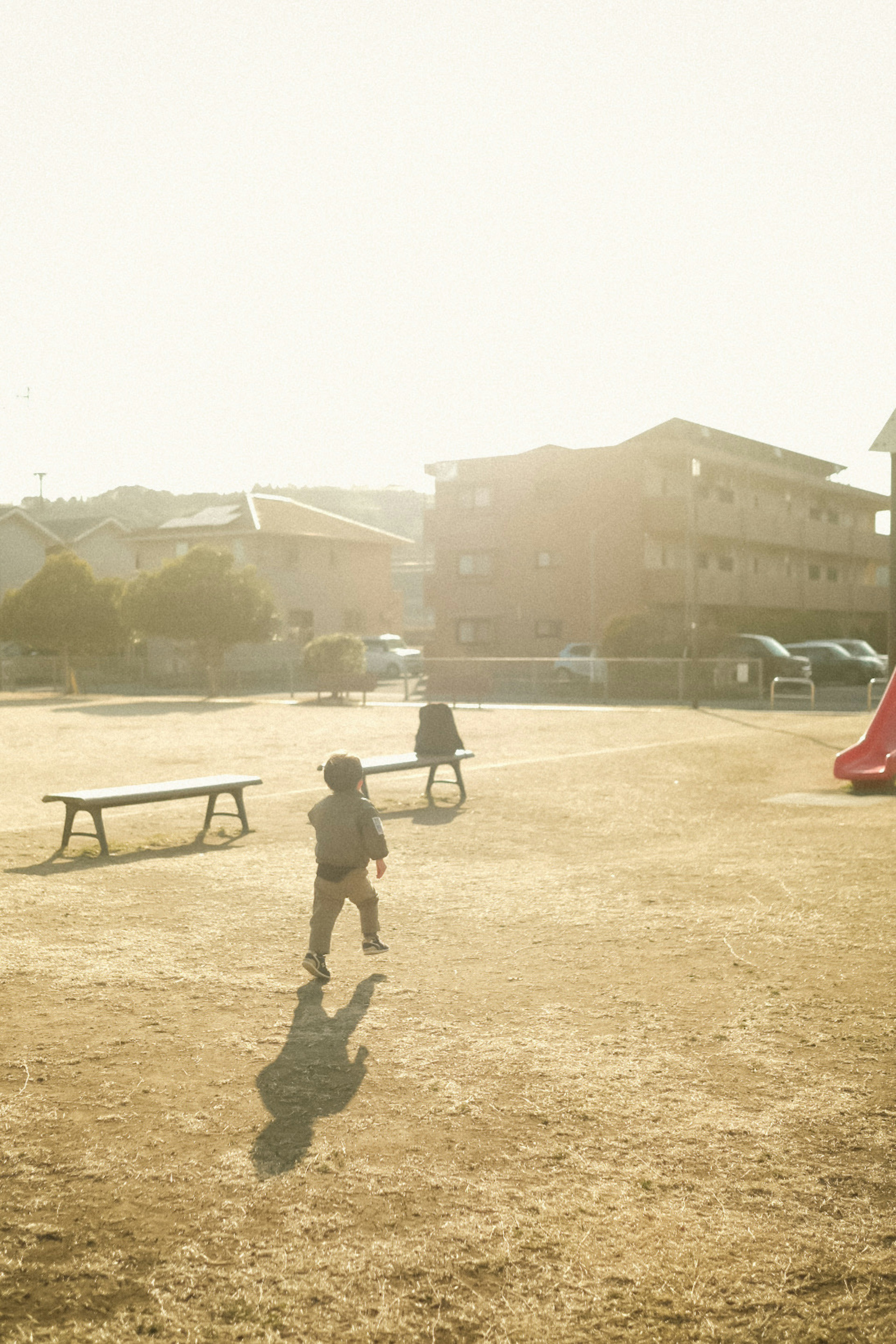 Silhouettes of children playing in a park with buildings in the background