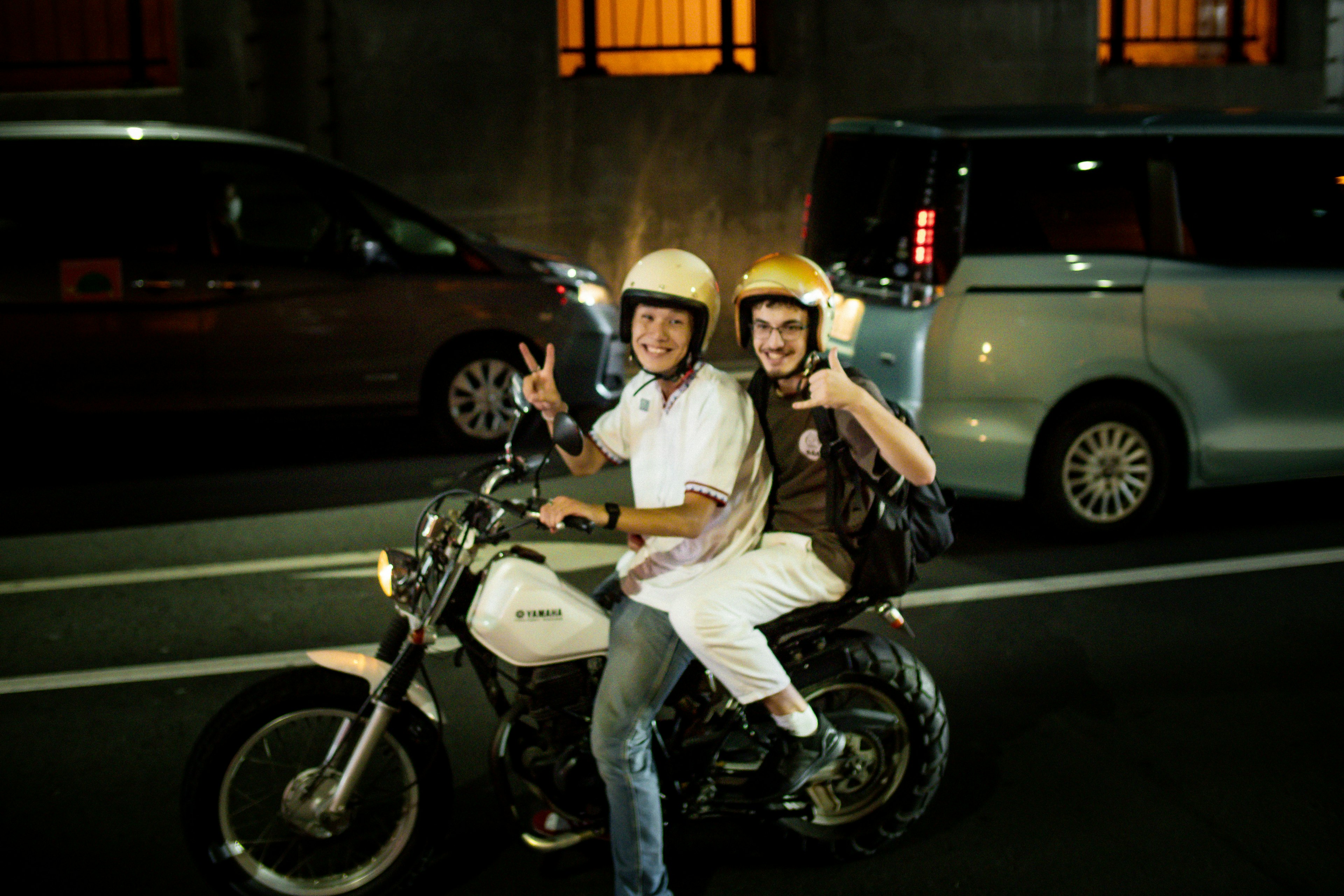 Two young people riding a motorcycle at night