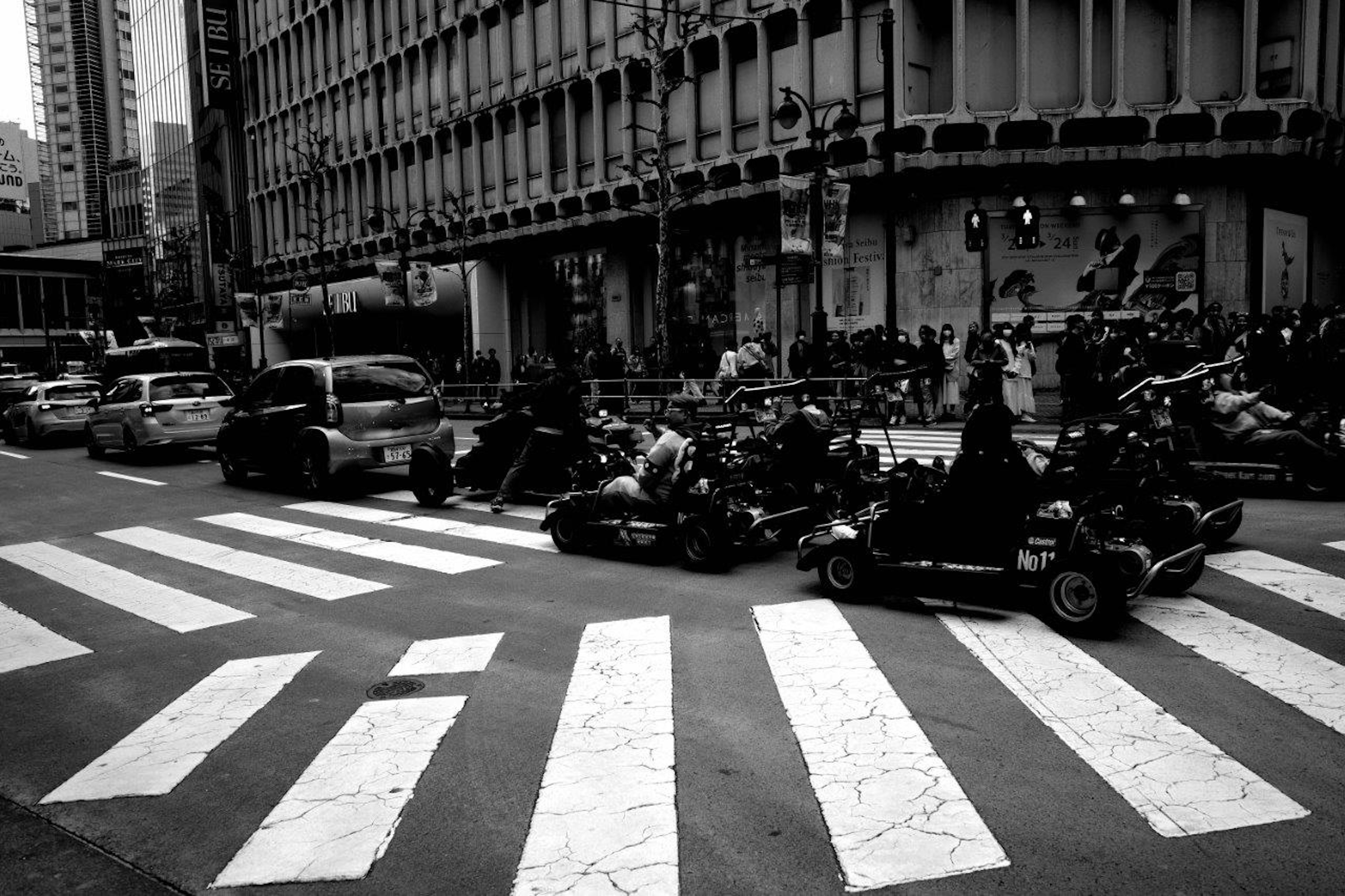 Scène urbaine avec des karts traversant un passage piéton en noir et blanc