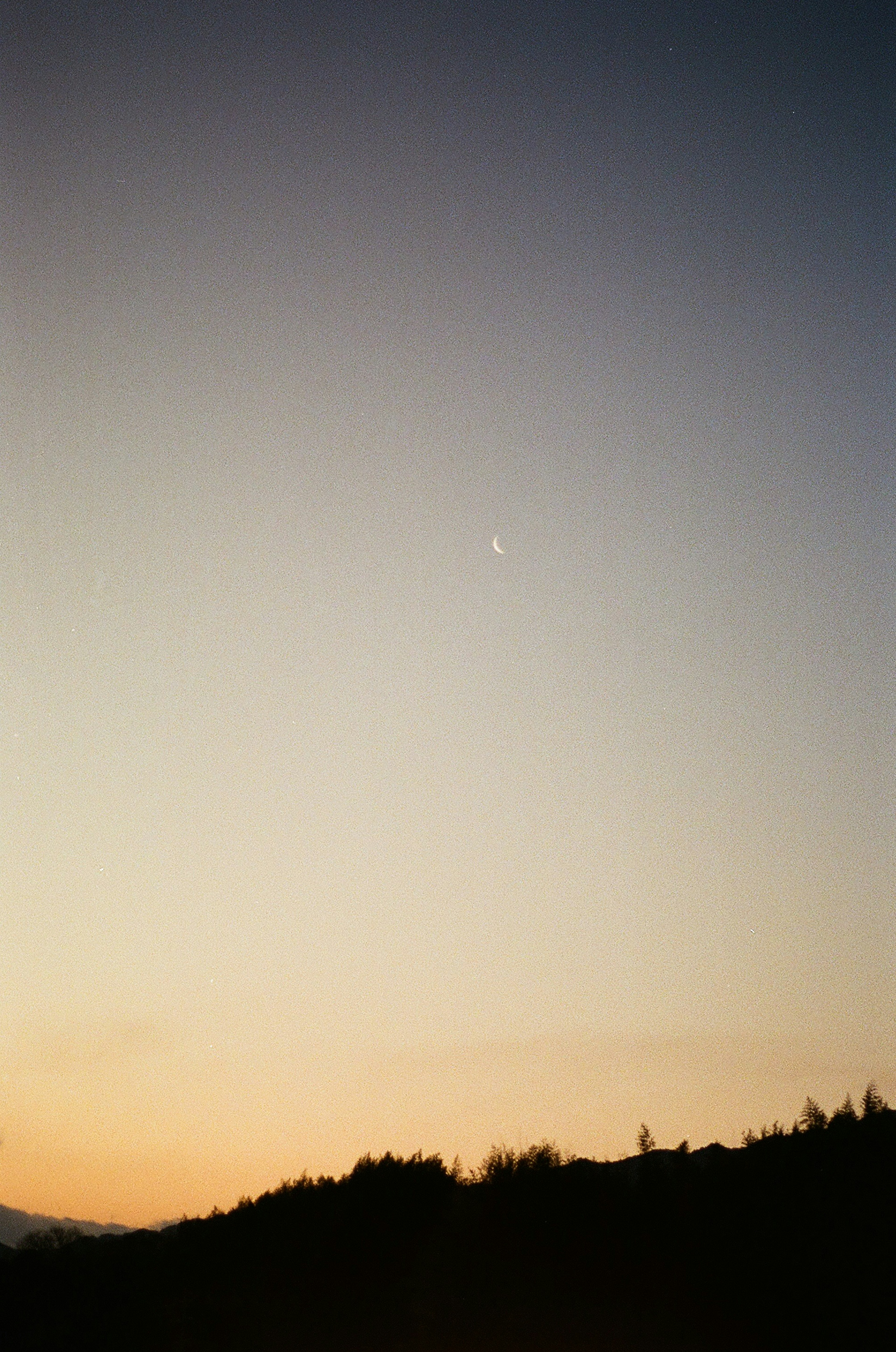 夕焼けの空に薄い月が浮かぶ風景