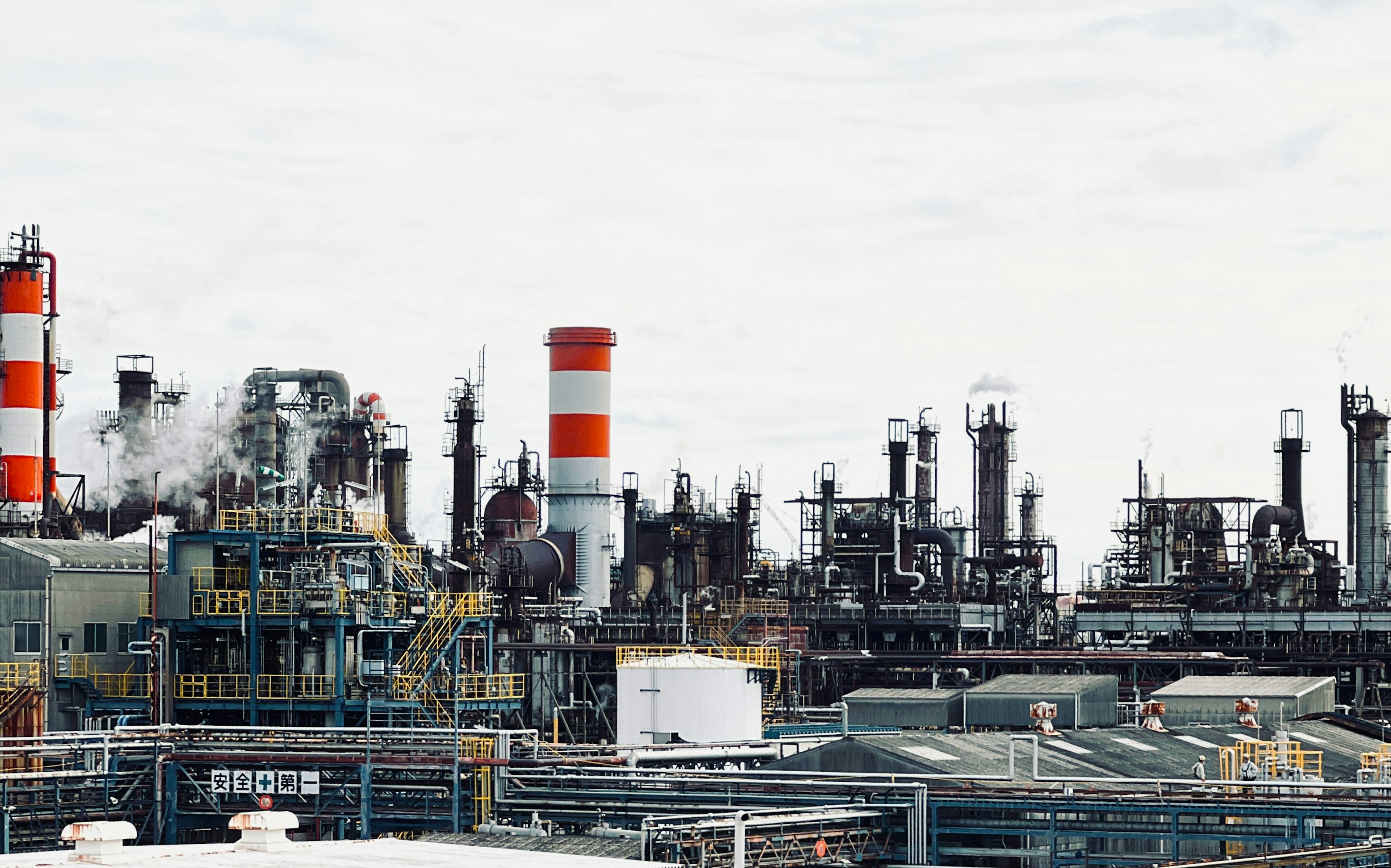 Paisaje industrial con chimeneas rojas y blancas y fábricas que emiten humo