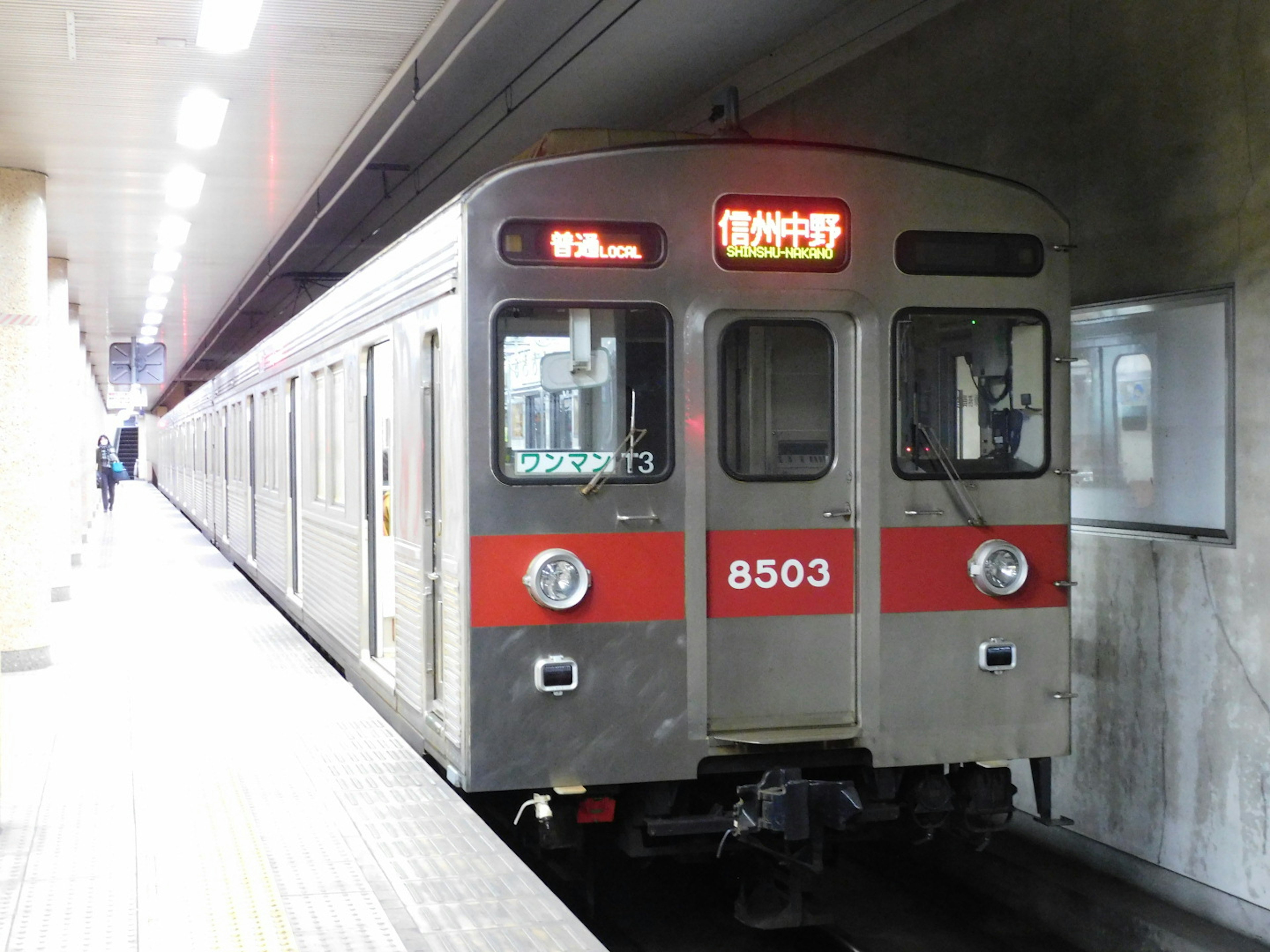 Subway train at a station featuring car number 8503 and a red stripe